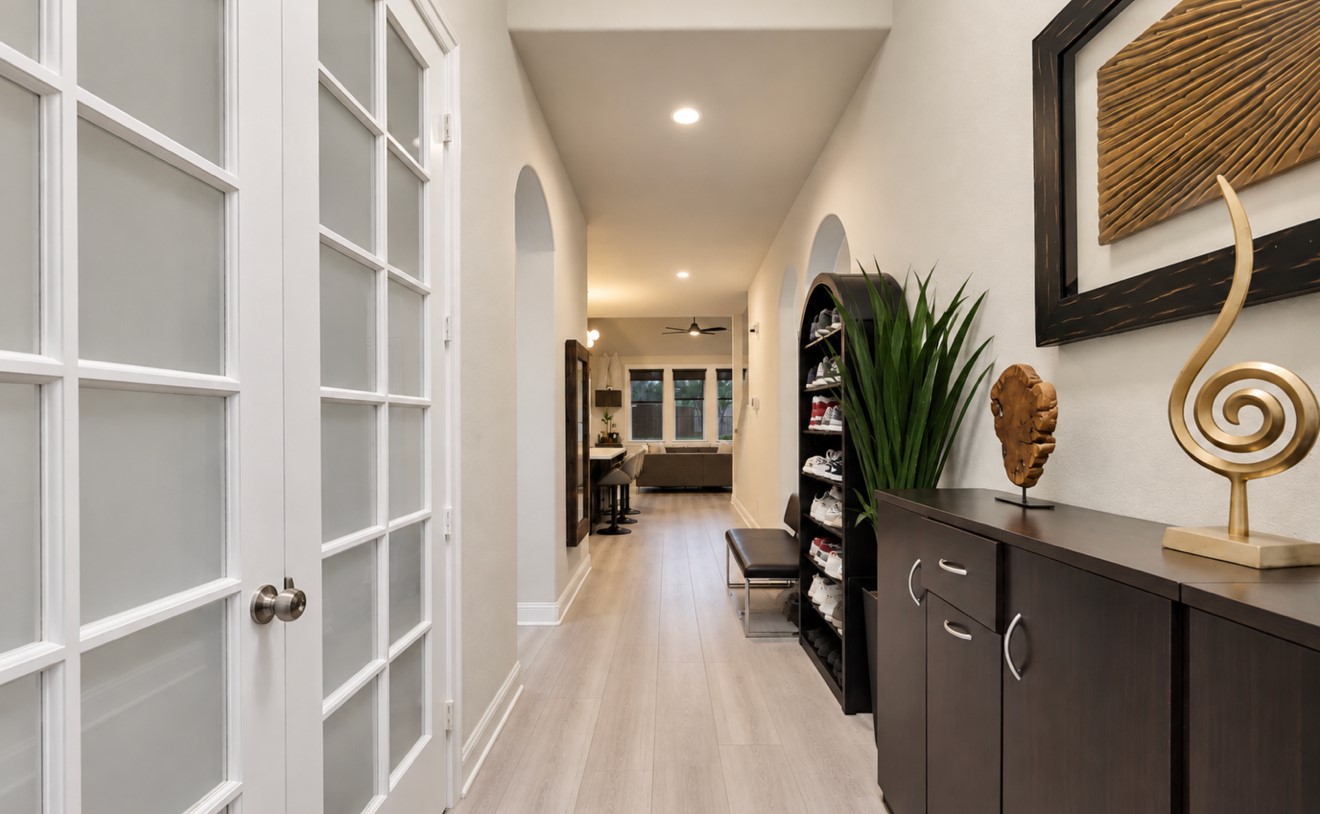 An inviting foyer with high ceilings, elegant arched openings, recessed lighting, and updated flooring creates a welcoming entrance that flows into the main living area.