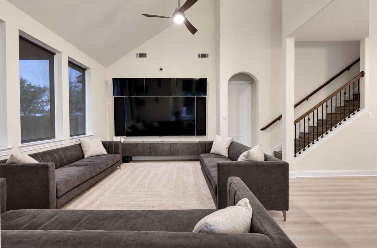 Inviting living area featuring high ceilings, updated flooring, and abundant natural light. The open layout connects to the kitchen and dining area for easy everyday living and entertaining, with convenient access to the staircase leading upstairs.