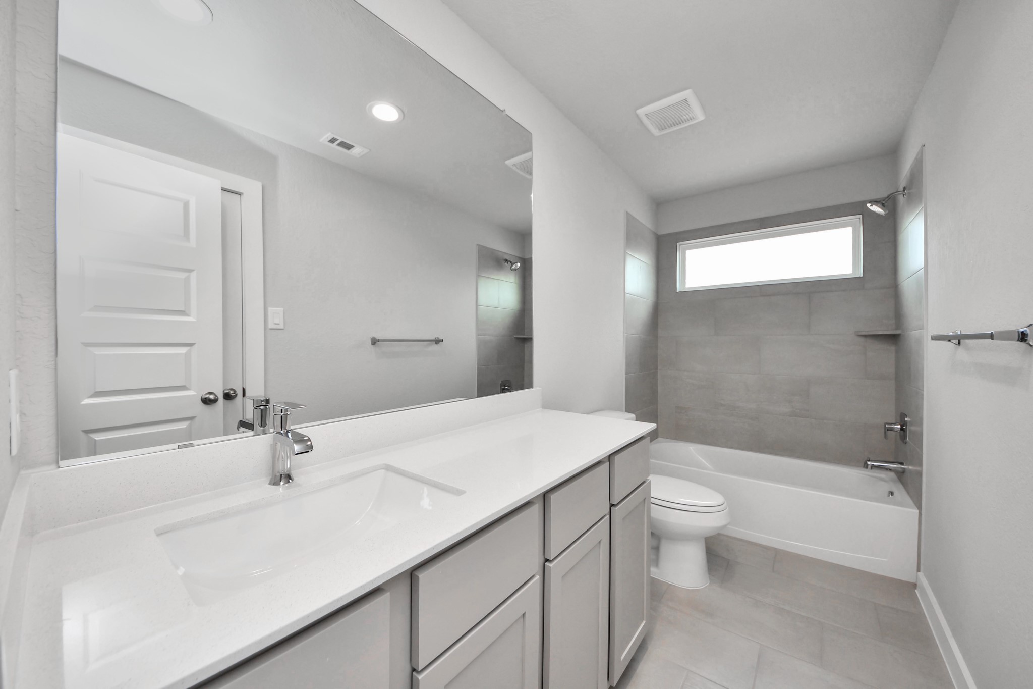 Secondary bath features tile flooring, bath/shower combo with tile surround, light stained wood cabinets, beautiful light countertop. Sample photo of completed home with similar floor plan. Actual colors and selections may vary.