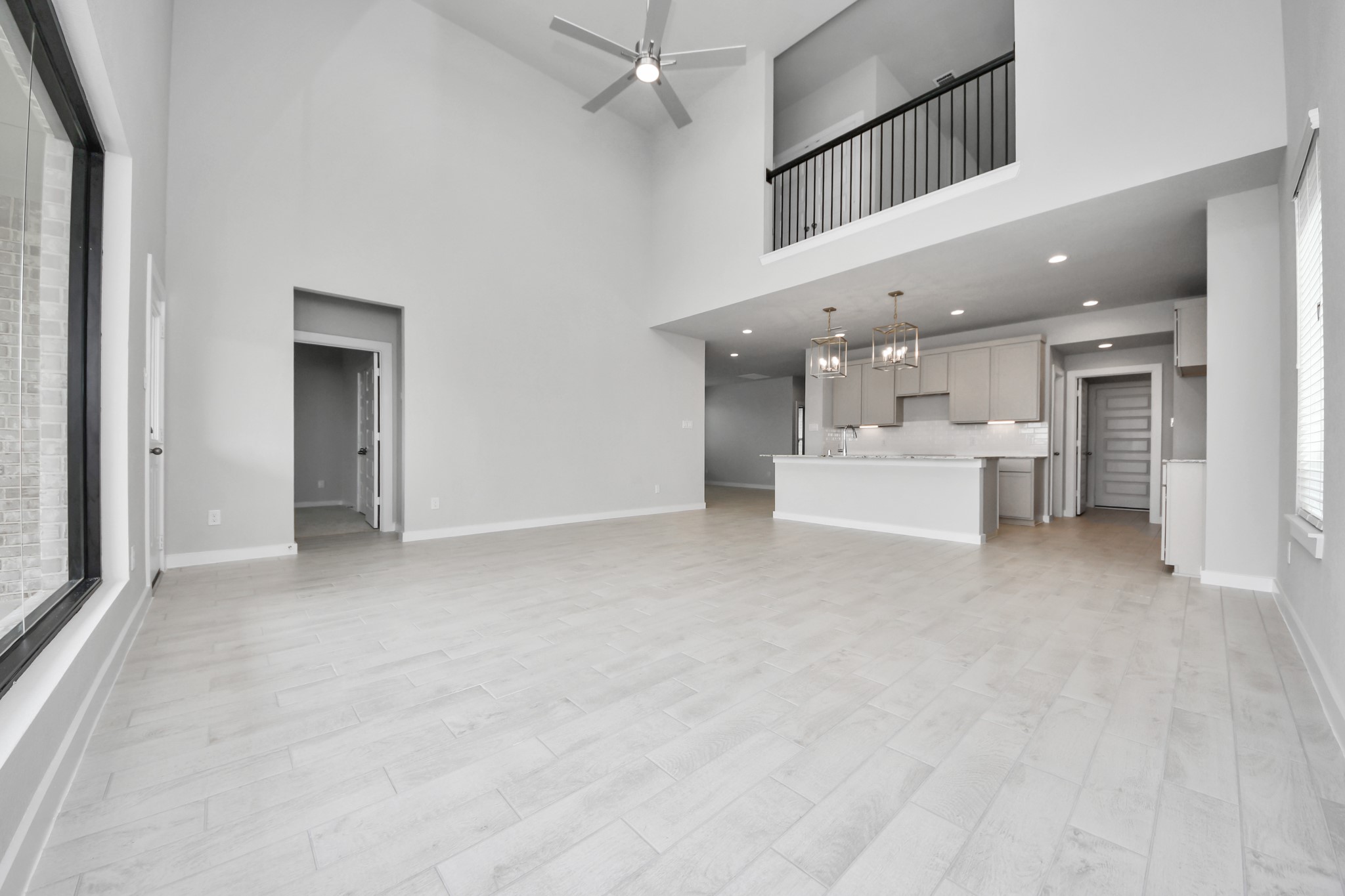 Relax and unwind in this inviting family room, illuminated by abundant natural light streaming in through tall windows, complemented by high ceilings and stunning flooring. Stay comfortable year-round with the gentle breeze from the ceiling fan, creating the perfect atmosphere for family gatherings. Sample photo of completed home with similar floor plan. Actual colors and selections may vary.
