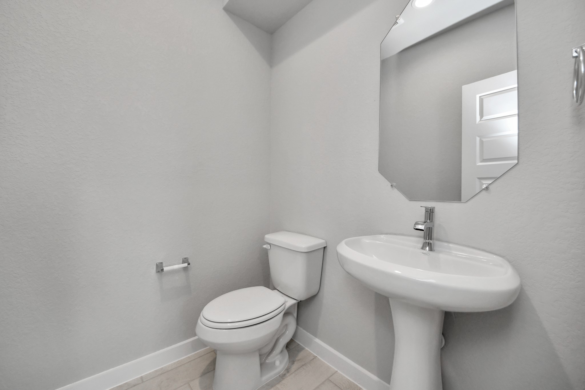 This half bathroom features a stylish pedestal sink, modern hardware, and bright recessed lighting, creating a sleek and inviting space. Sample photo of completed home with similar floor plan. Actual colors and selections may vary.