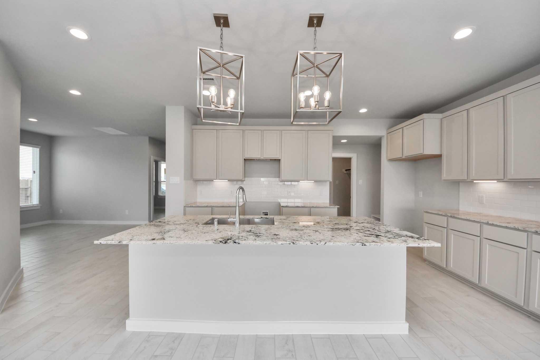 This kitchen is by far any chefs dream! This spacious kitchen features high ceilings, light stained wood cabinets, granite countertop, SS appliances, modern tile backsplash, recessed lighting, extended counter space, granite kitchen island with double sink, and space for breakfast bar, and a walk-in pantry all overlooking your huge family room. Sample photo of completed home with similar floor plan. Actual colors and selections may vary.