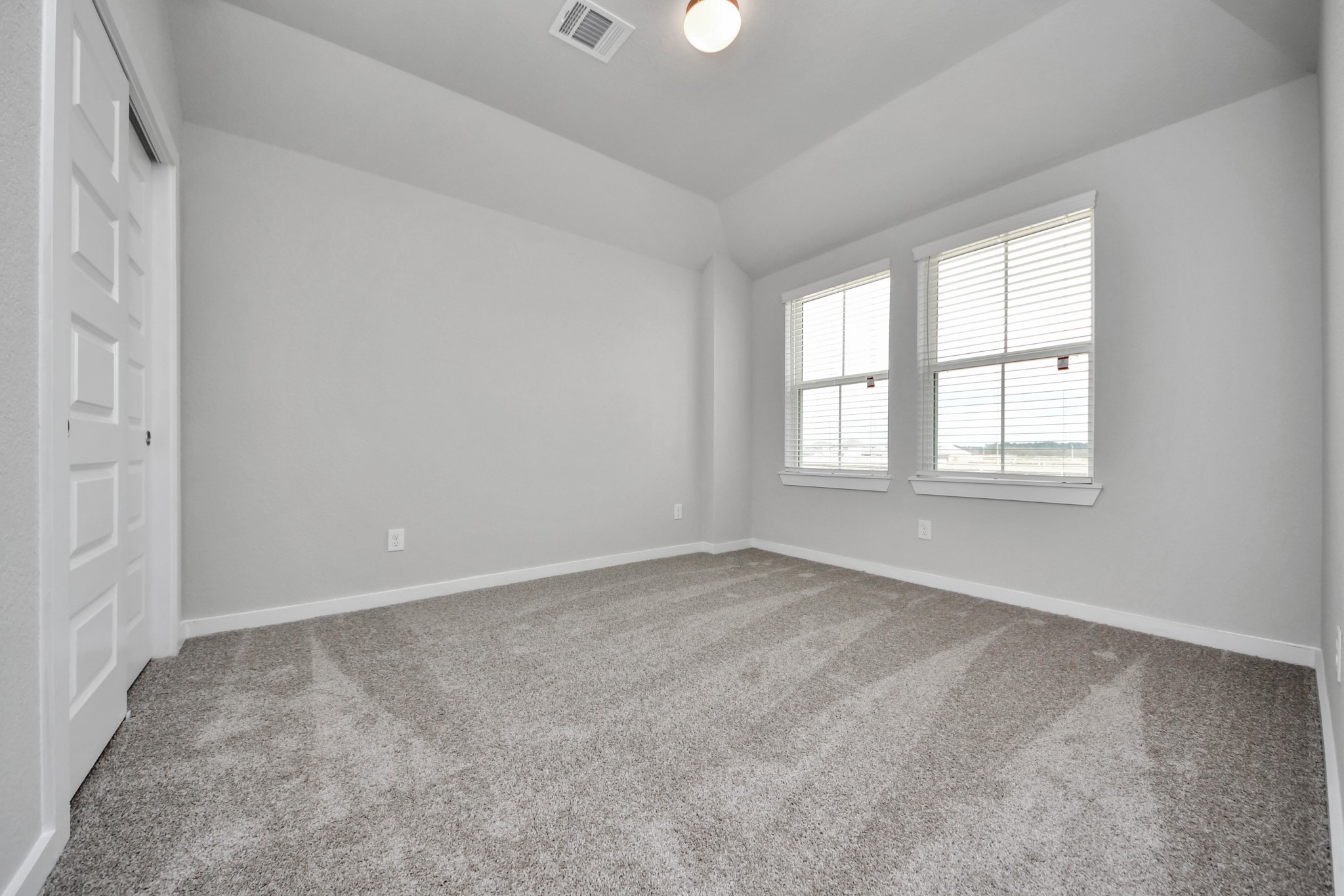 Secondary bedroom features plush carpeting, large windows that let in plenty of natural light, bright paint, and spacious closets. Sample photo of completed home with similar floor plan. Actual colors and selections may vary.