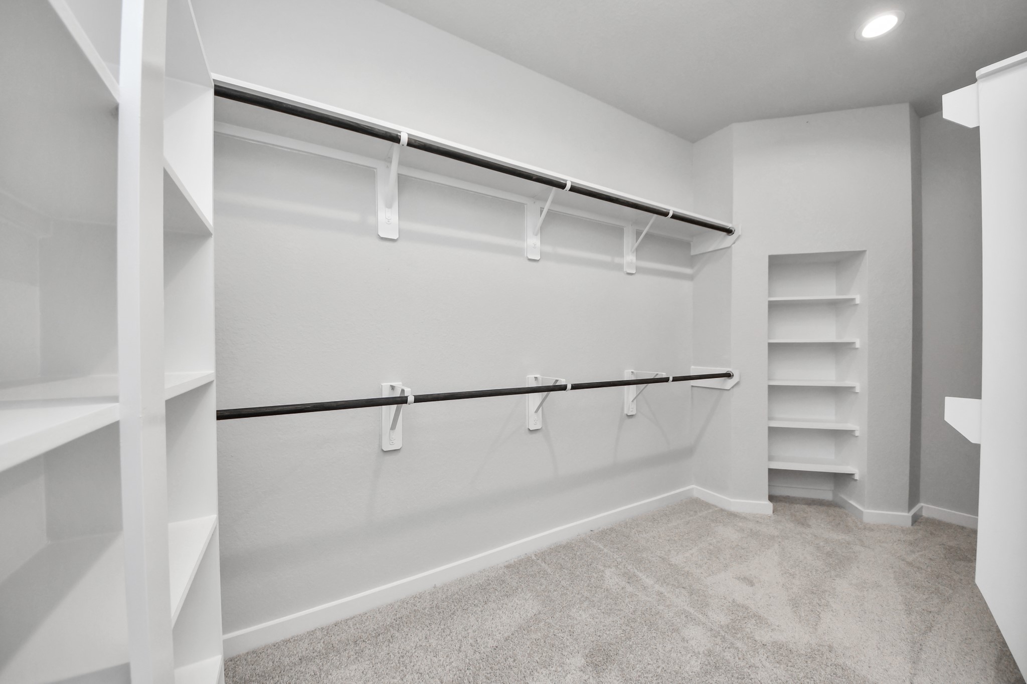 Walk-in closet that epitomizes luxury and practicality. This generously sized space features built-in shelving, offering abundant room for impeccable organization. High ceilings and recessed lighting create a bright and welcoming ambiance. Sample photo of completed home with similar floor plan. Actual colors and selections may vary.