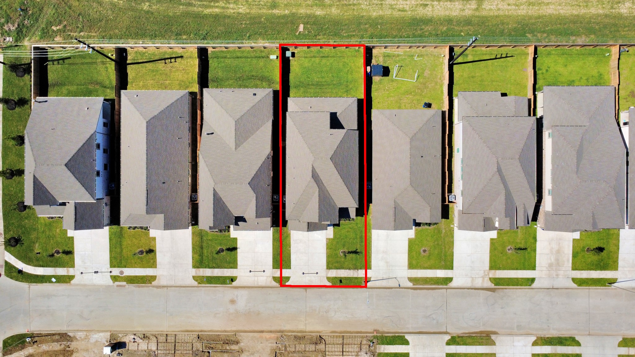 An aerial view of a spacious subdivision lot, highlighting a well-maintained yard and a fully fenced perimeter, offering both privacy and expansive outdoor space.