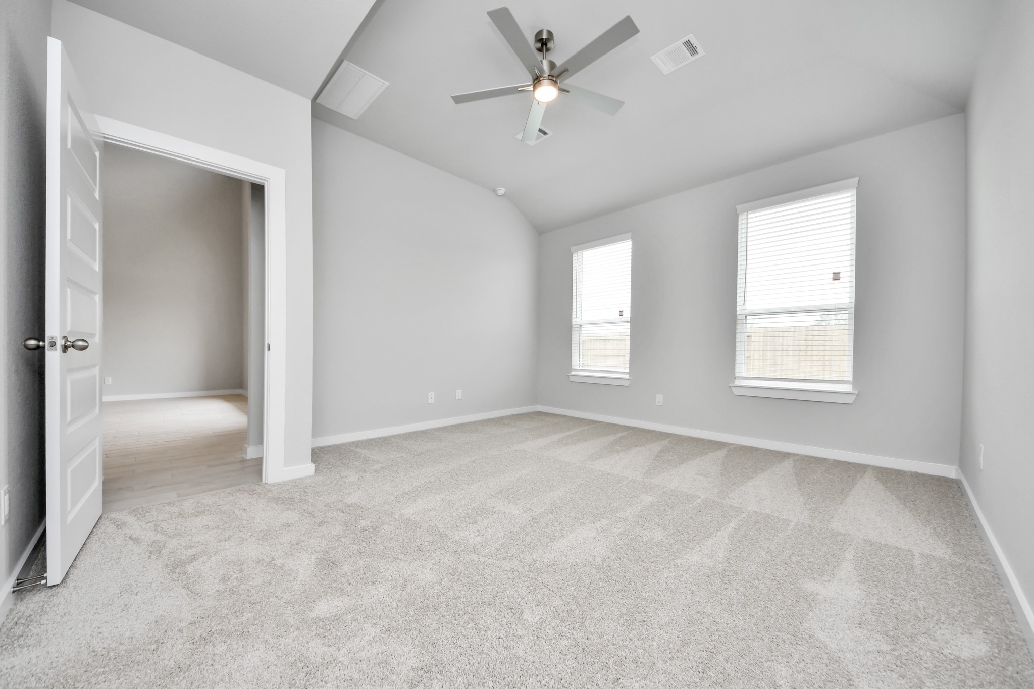 Escape and relax in the exquisite primary suite, a haven to unwind after a long day. The spacious room, located on first floor, boasts plush carpeting, soothing paint tones, high ceilings, and expansive windows adorned with privacy blinds. Sample photo of completed home with similar floor plan. Actual colors and selections may vary.