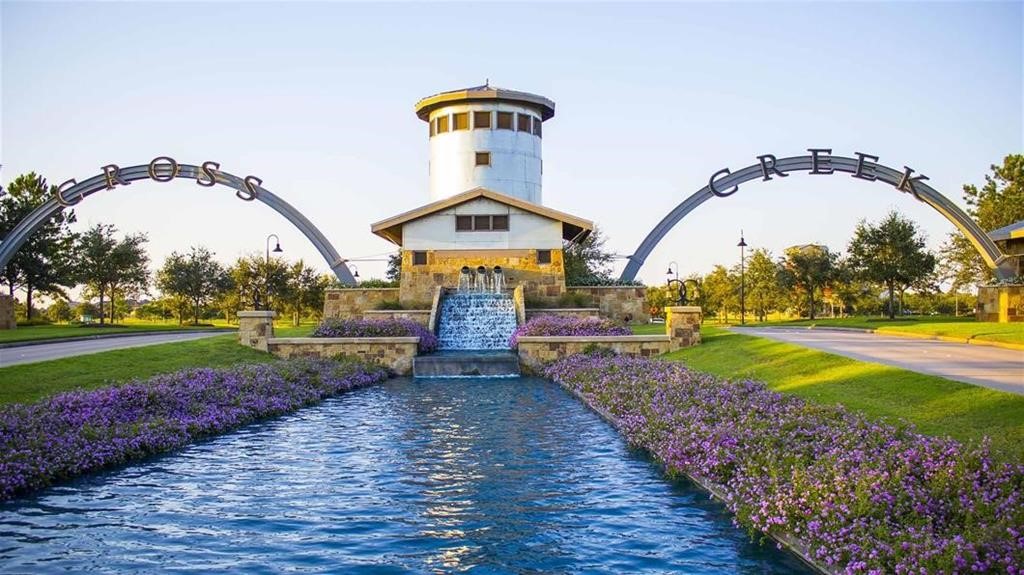 Experience the charm of Cross Creek Ranch with its welcoming entrance featuring a scenic waterfall, lush landscaping, and a serene waterway lined with vibrant flowers, setting the tone for a beautiful community living.