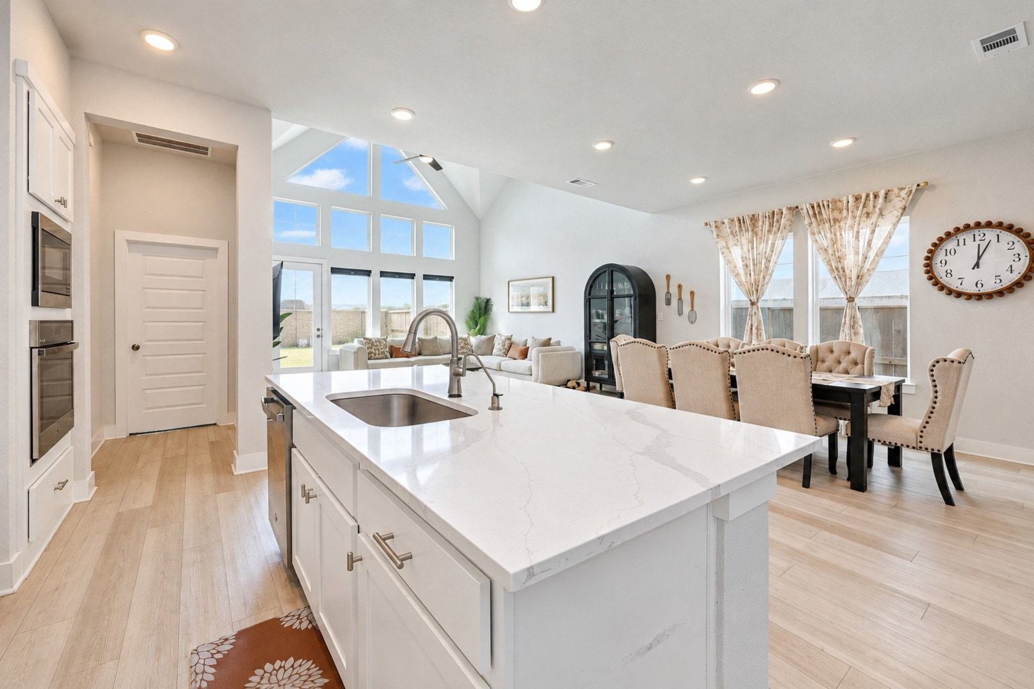 Open-concept living area featuring a modern kitchen with a large island, elegant dining space, and a spacious seating area, all accented by abundant natural light from floor to ceiling windows.