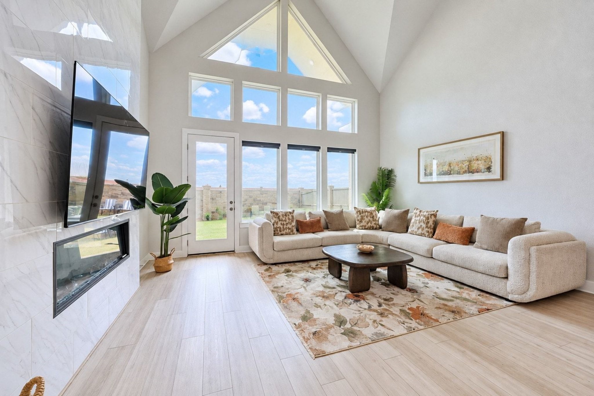 Inviting living room with cathedral ceilings, panoramic windows, and a contemporary electric fireplace, perfect for relaxation and entertaining.