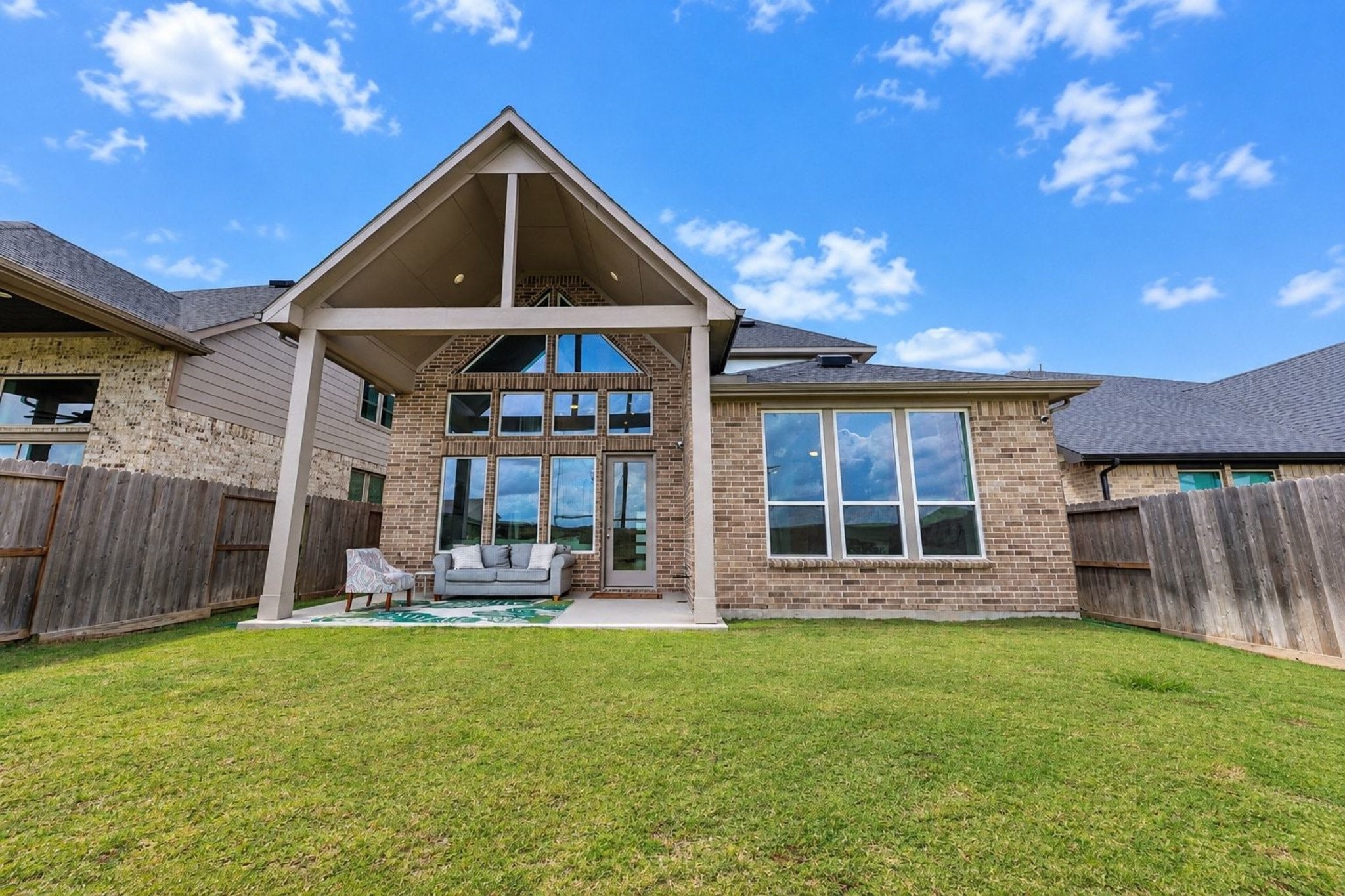 Spacious backyard with a two story covered patio and elegant brick exterior, perfect for outdoor entertaining.