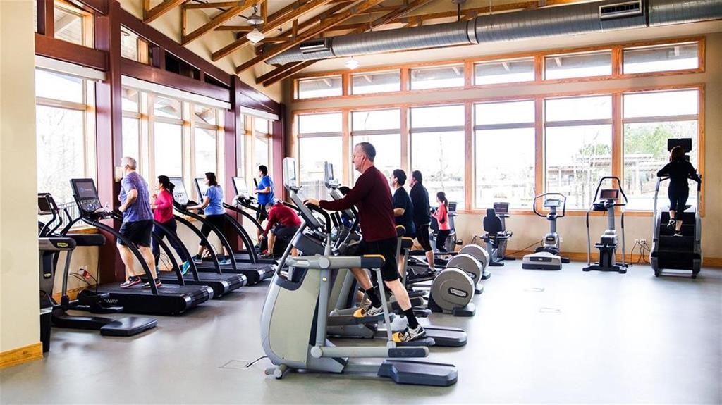 Spacious fitness center with large windows, abundant natural light, and a variety of exercise machines.