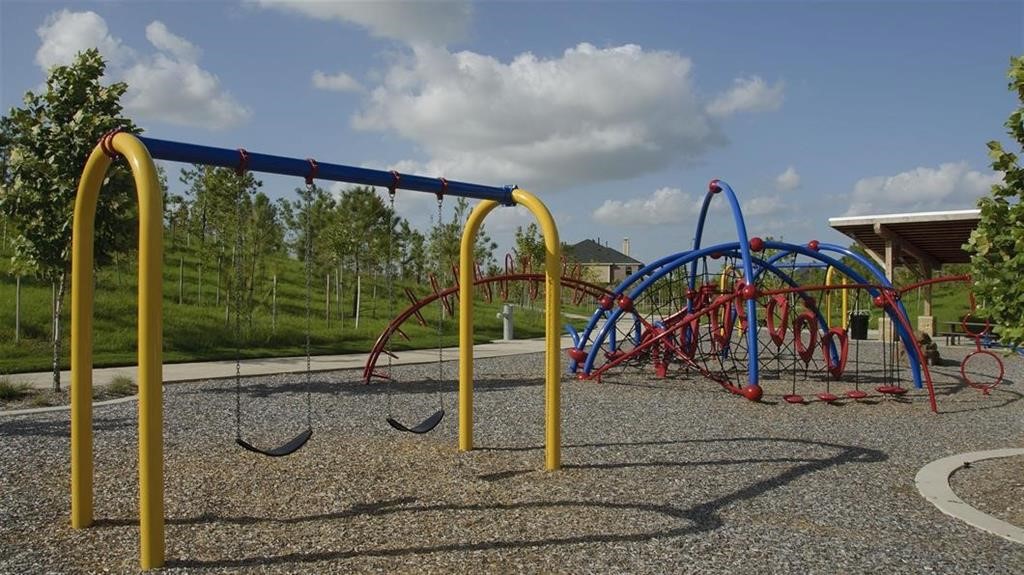 Another community playground featuring colorful swings and climbing structures, set against a backdrop of lush greenery and open skies. Perfect for family fun and outdoor activities.