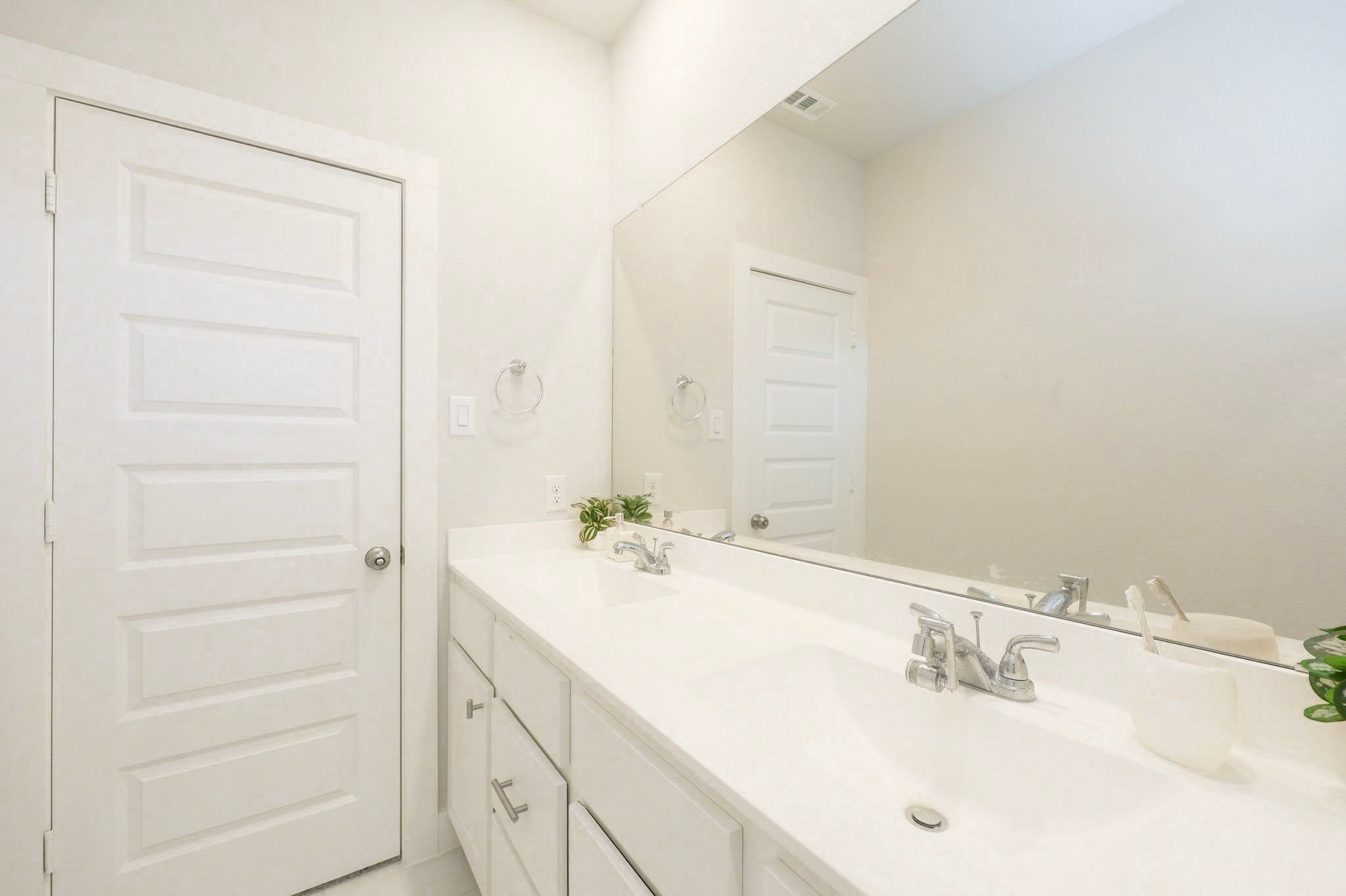 Bright and modern bathroom on 2nd floor featuring a double vanity with sleek fixtures, ample storage, and a large mirror enhancing the sense of space.