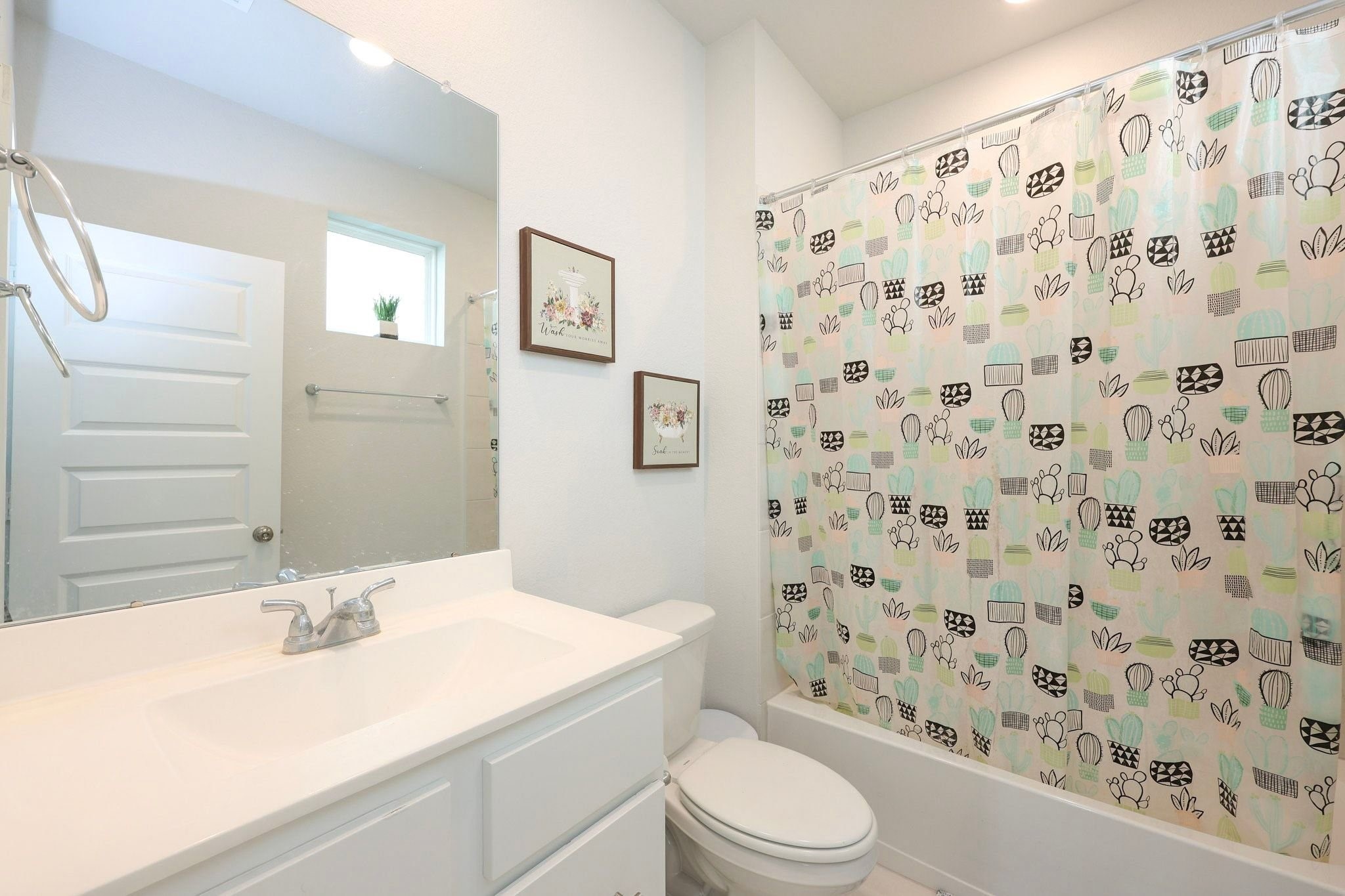 Secondary bathroom on 1st floor with a window - featuring a sleek white vanity and a tub with shower.