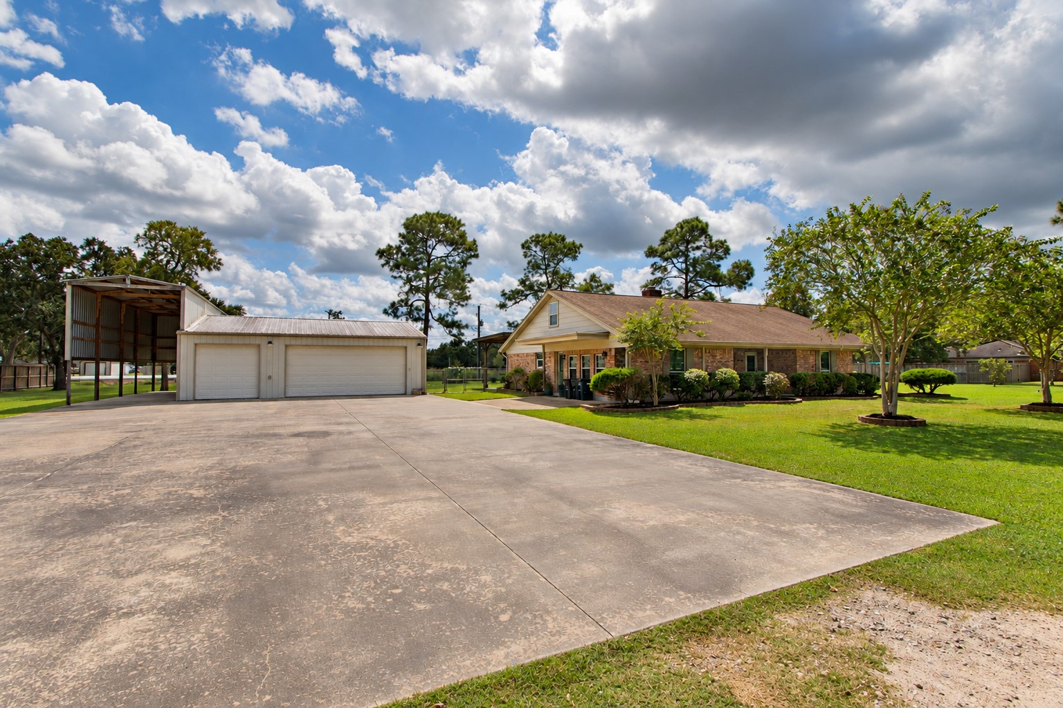 Expansive concrete driveway with a spacious garage plus additional covered RV/boat storage, offering plenty of room for vehicles, recreational equipment, and more.