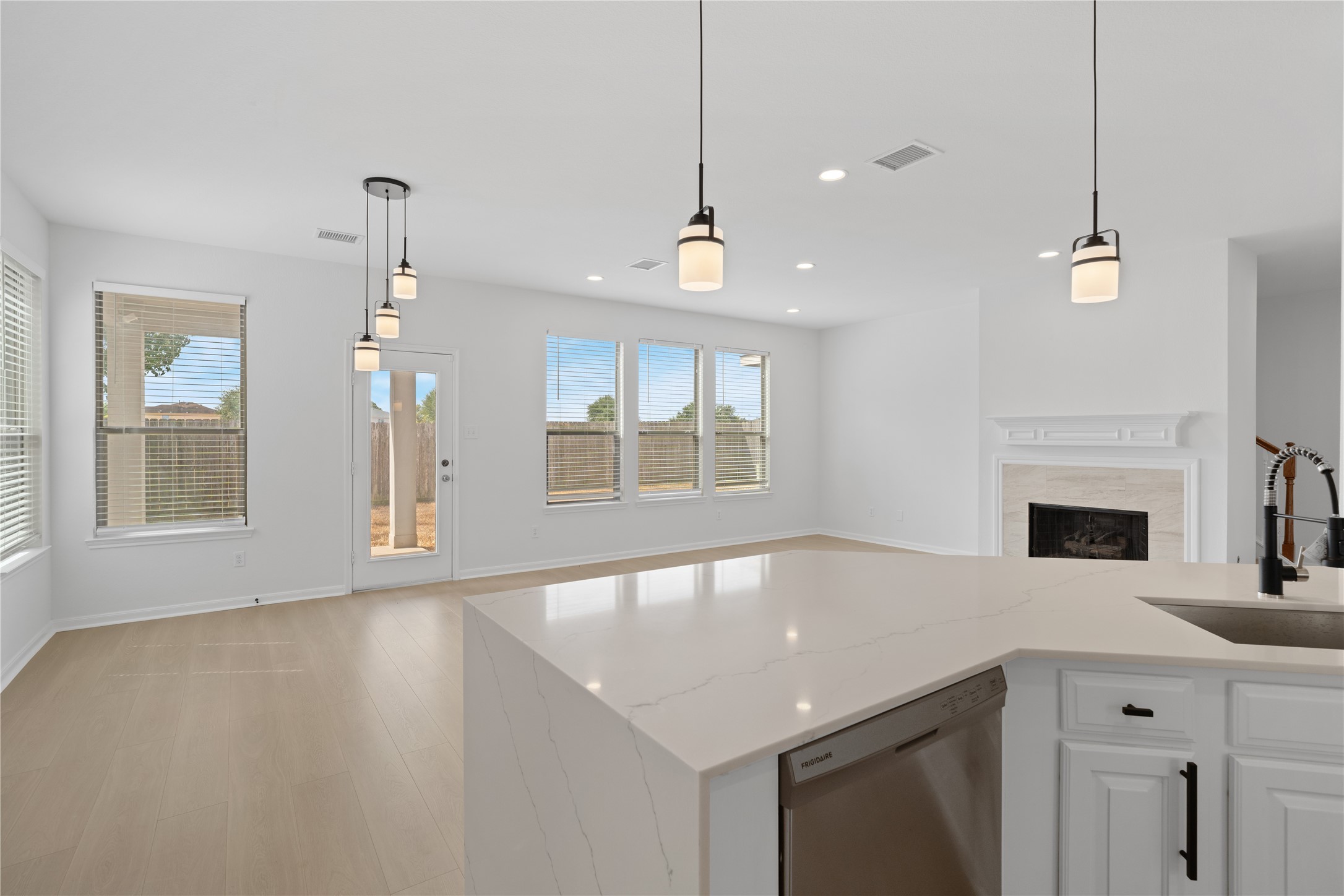 Kitchen & Living Area  Large peninsula provides expansive prep and serving space while maintaining an open view toward the fireplace, dining area, and backyard-facing windows.