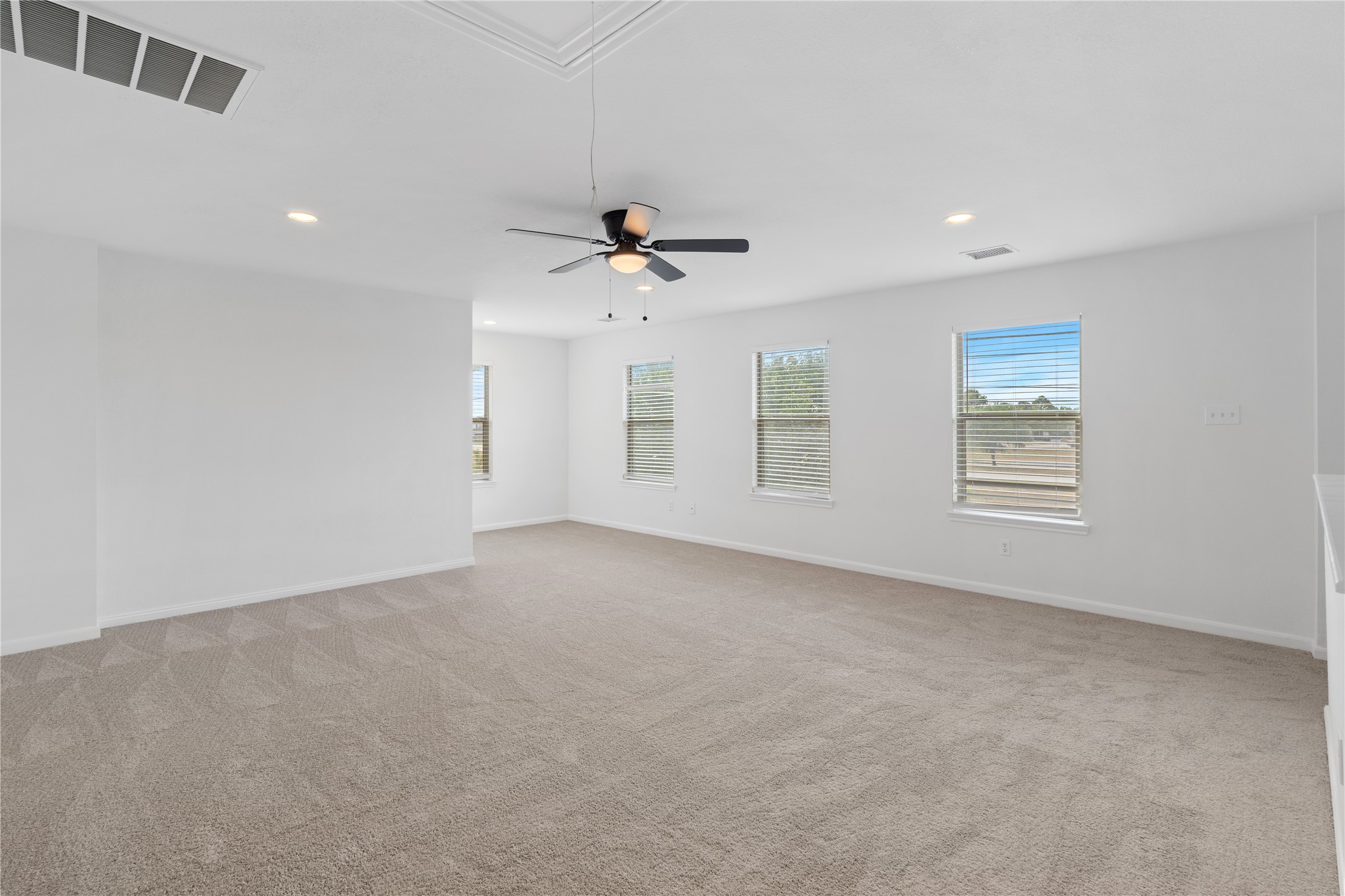 Game Room / Flex Space  Expansive upstairs flex space with multiple windows, recessed lighting, a ceiling fan, and plenty of room for media, recreation, or additional lounge space.