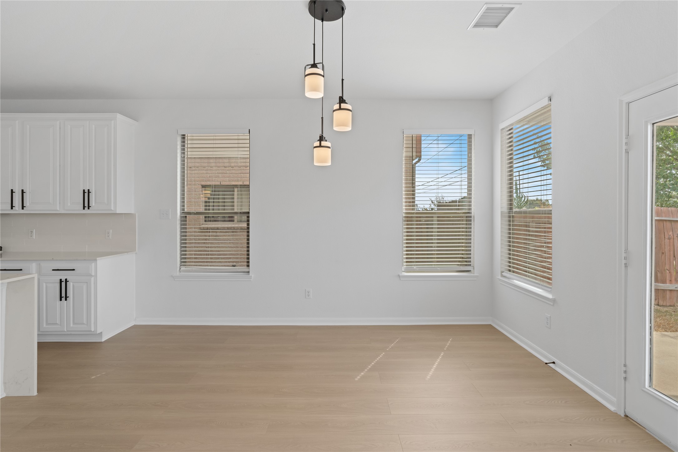 Dining / Breakfast Area  Sunlit dining area is surrounded by multiple windows and accented by contemporary pendant lighting, with convenient access to the backyard through a glass-paneled door.