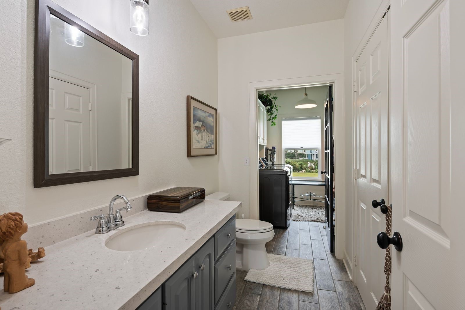 Stylish, Elegant & Modern!  Convenient half bathroom with custom countertops, storage, framed mirror, custom fixtures and tile flooring.