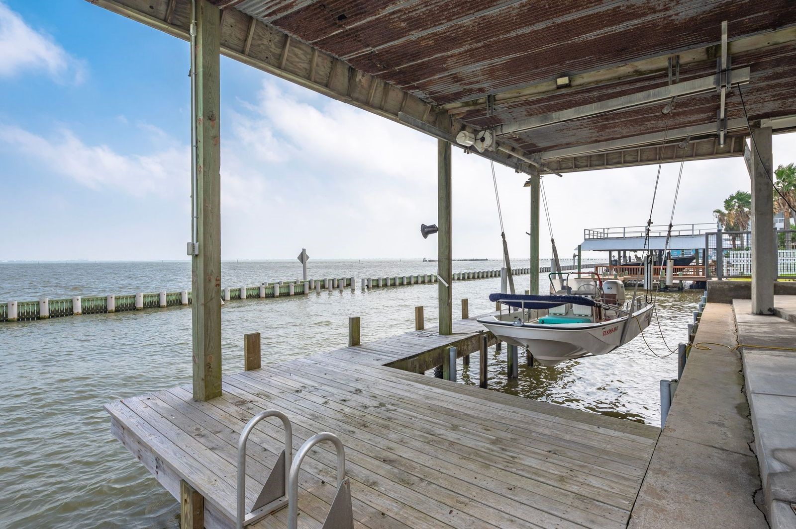 Enjoy Your Boat Day or Night!  Property boasts concrete bulkhead with boat house/decking and lift featuring 9 "wellers" for the pier; enjoy fishing Galveston Bay with deep water access direct to the Gulf of America.