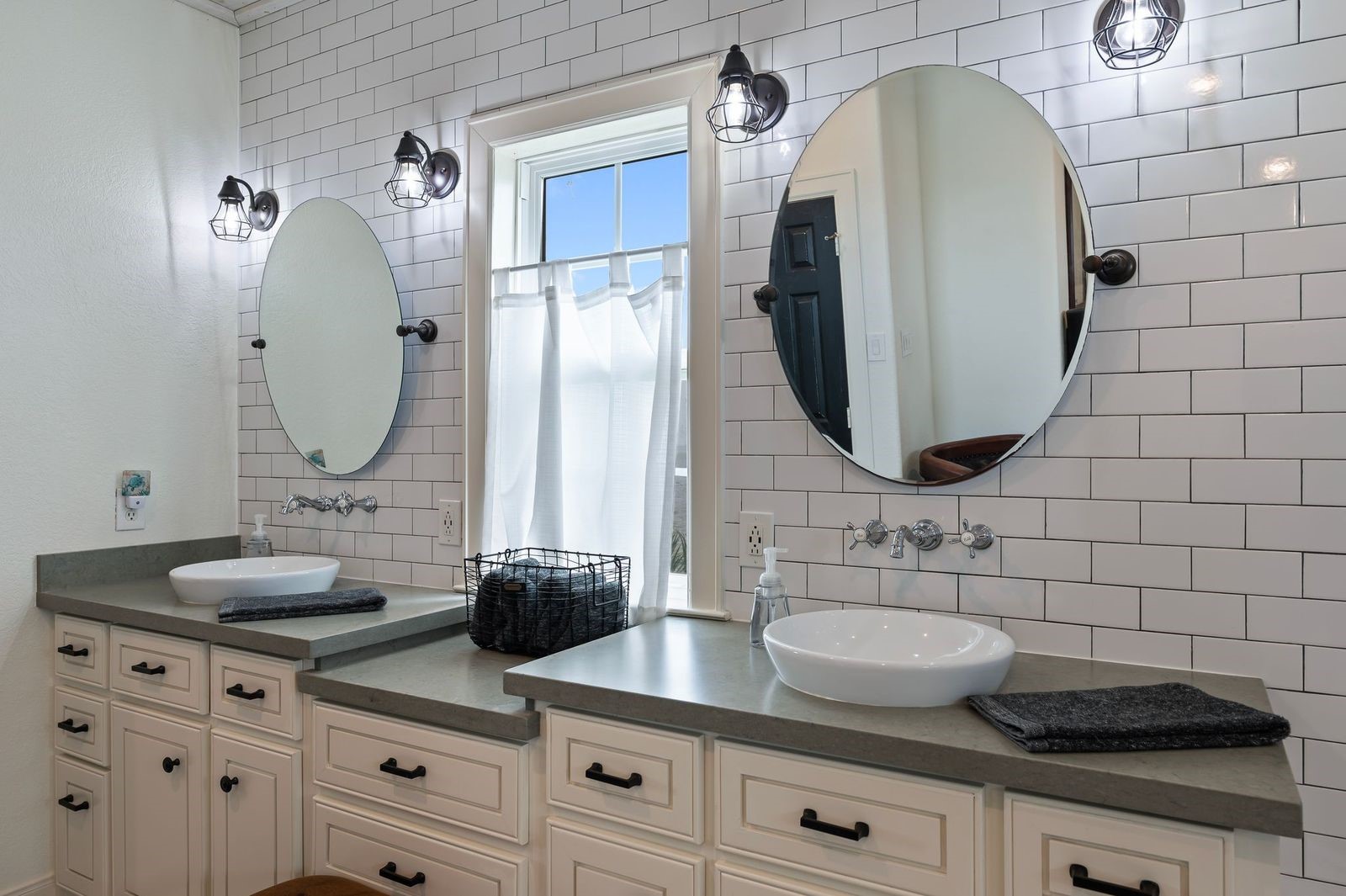 Modern, Vibrant Beachside Beauty! A detailed view of the primary bathroom with custom fixtures, bowl sinks, subway tile backsplash and custom mirrors.
