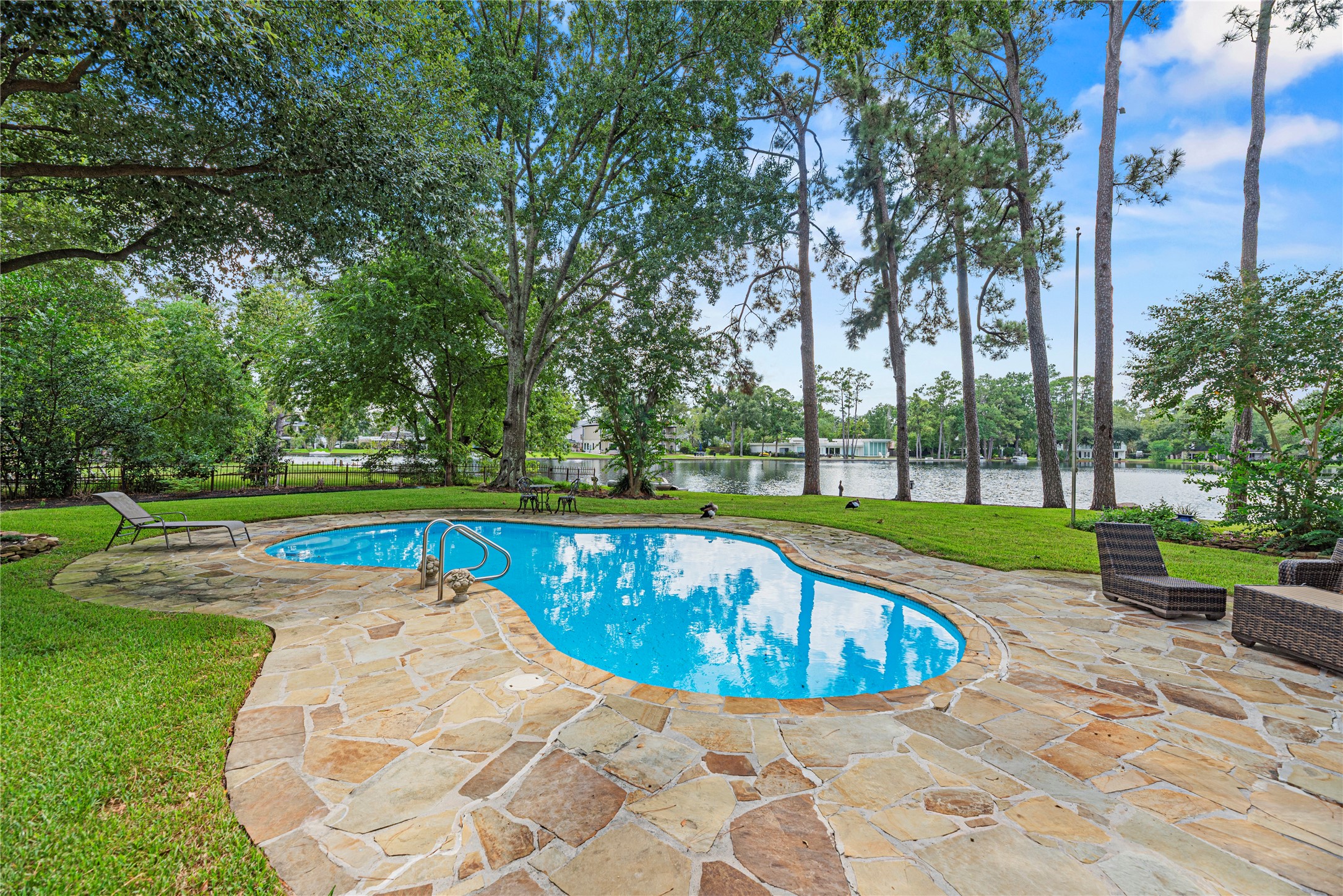 Sparkling pool, expansive patio, lush green space, and 105' of lakefront.