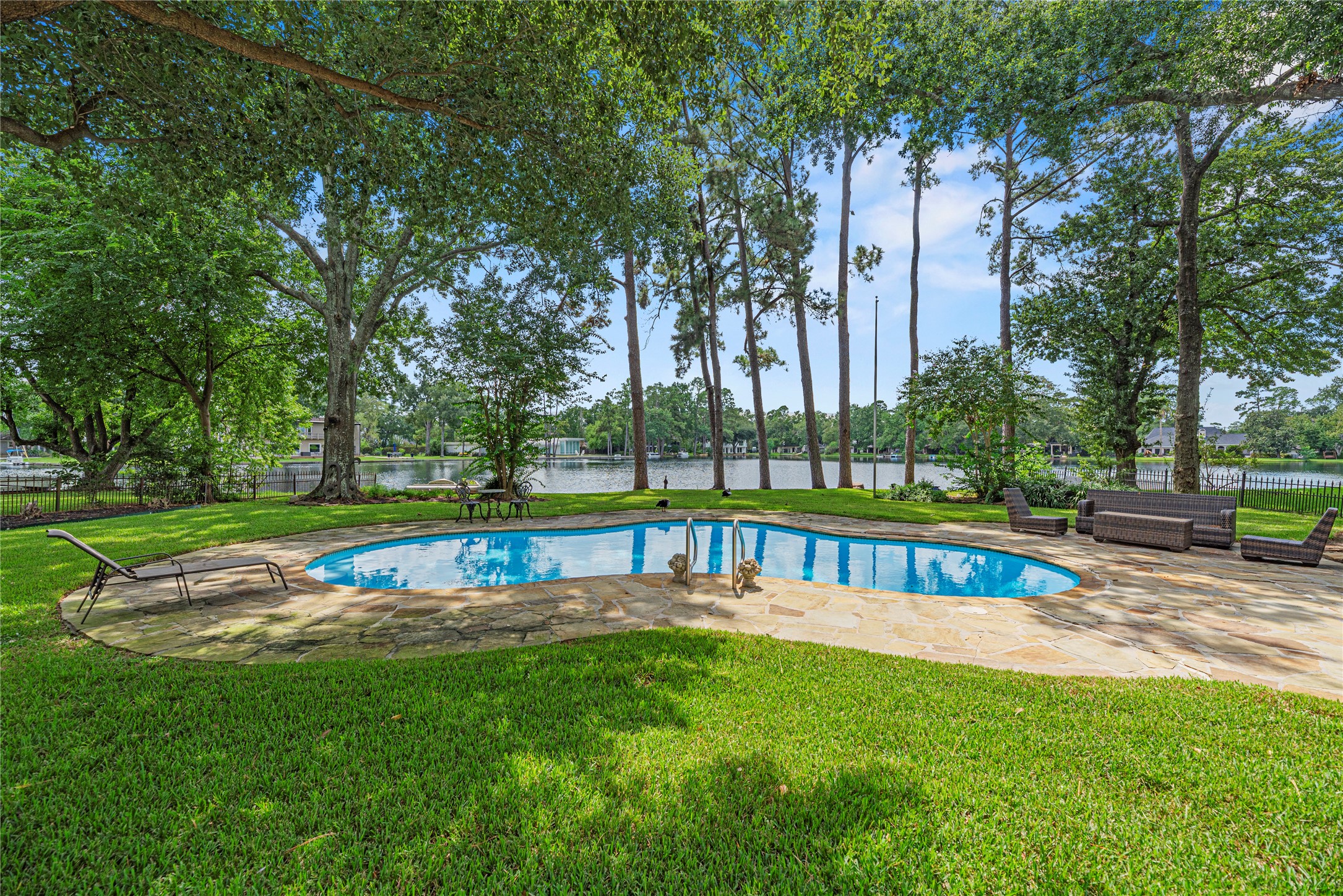 Sparkling pool, expansive patio, lush green space, and 105' of lakefront.
