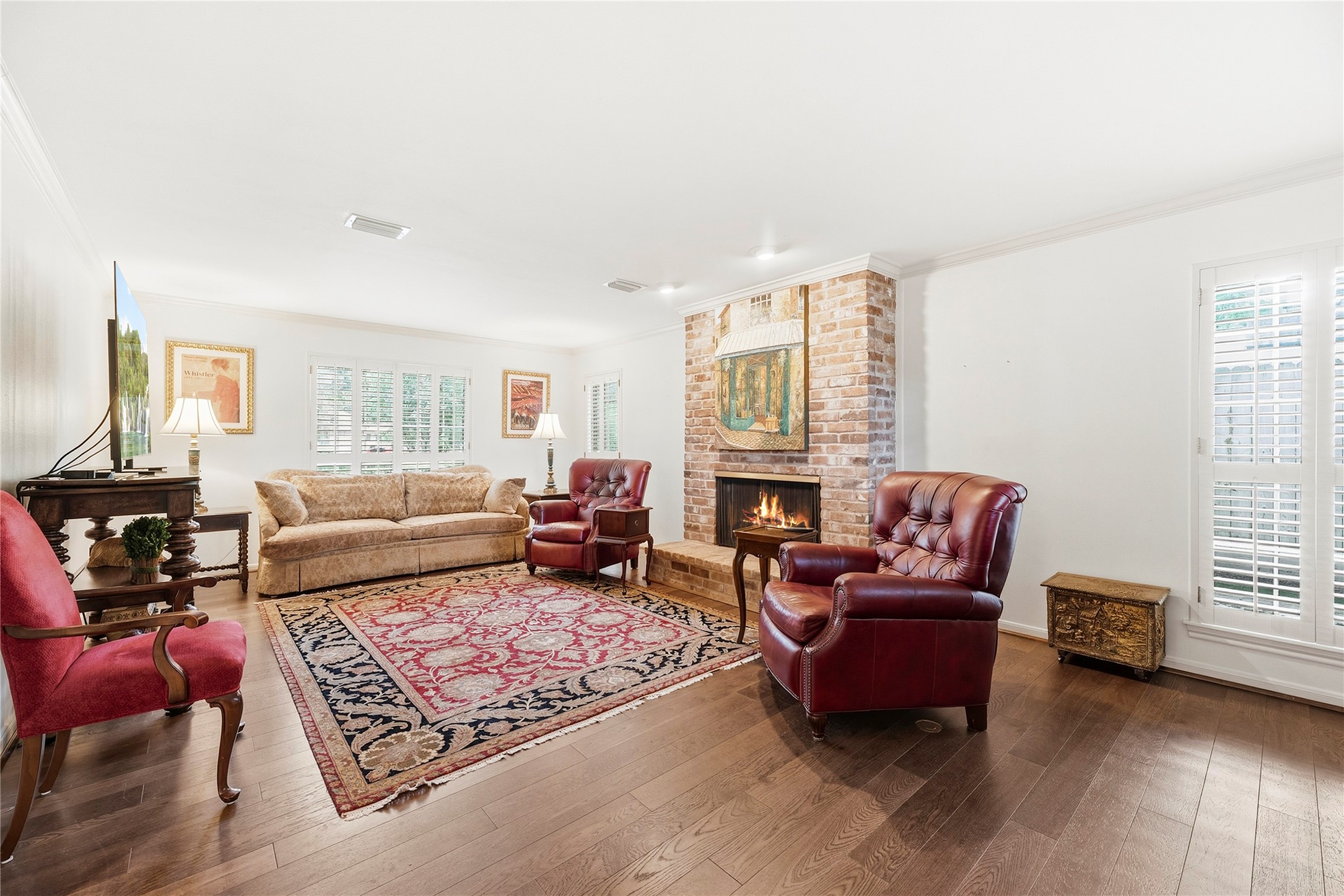 Spacious family room/den. Complete with wood floors, neutral paint, brick fireplace, and multiple large windows with plantation shutters.