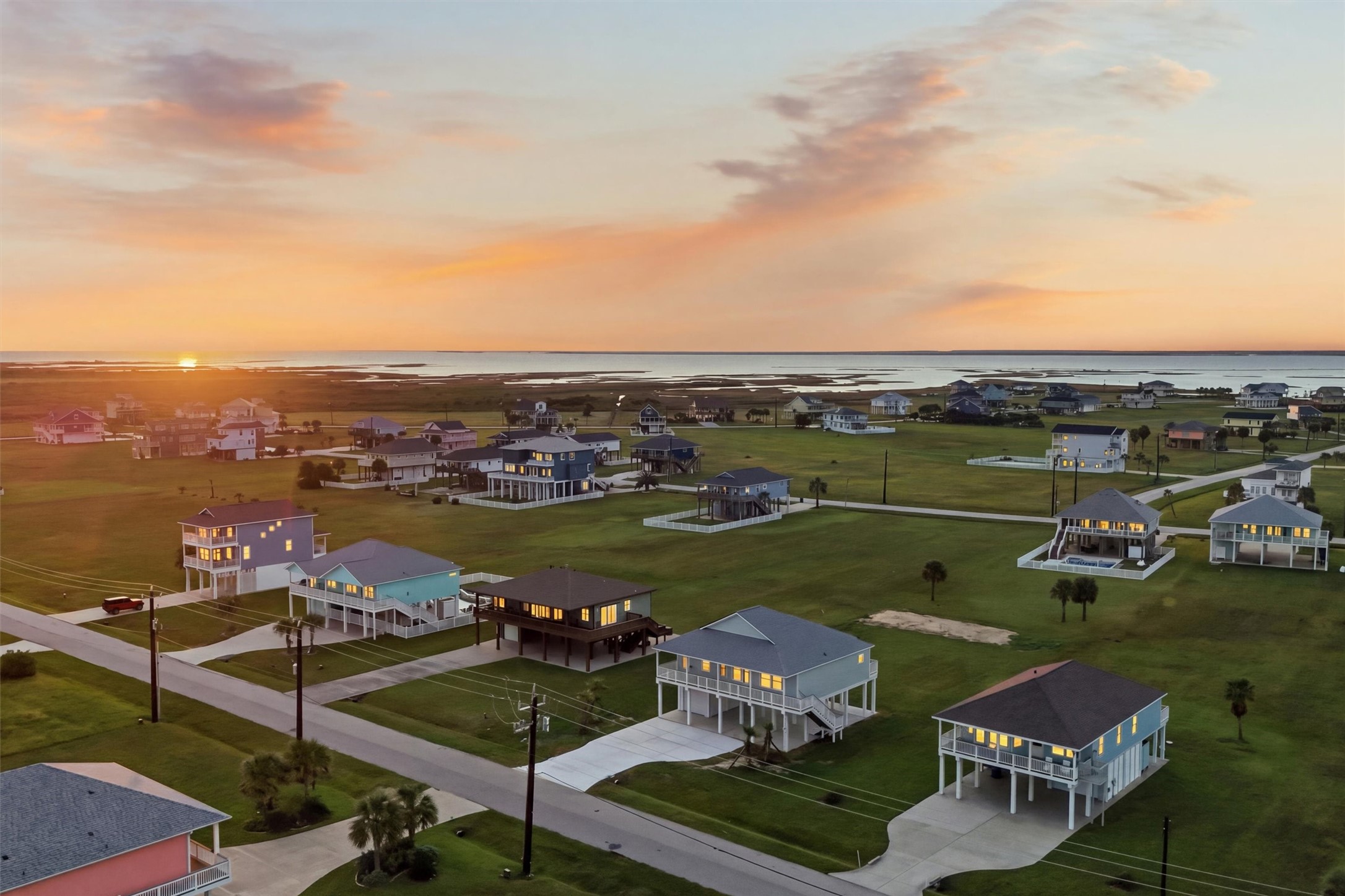 Charming coastal community with elevated homes, offering stunning sunset views over the water and expansive green spaces.