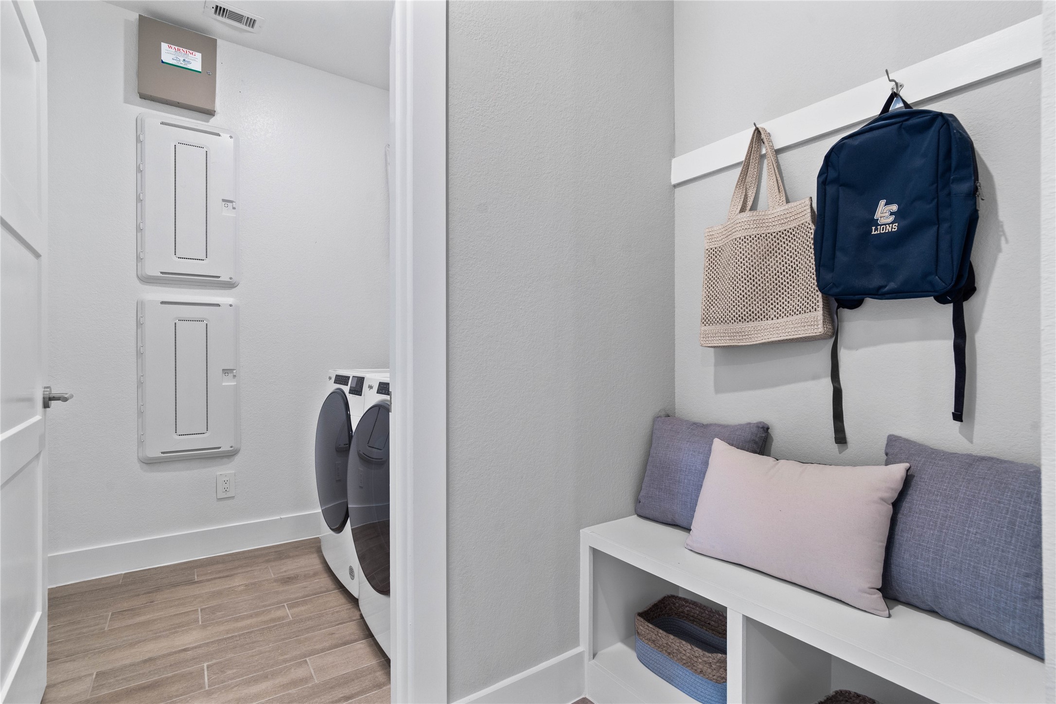 This dedicated area features a custom built-in bench with hooks, perfect for organizing coats, bags, and shoes right off the main hallway, keeping the rest of the home tidy.
