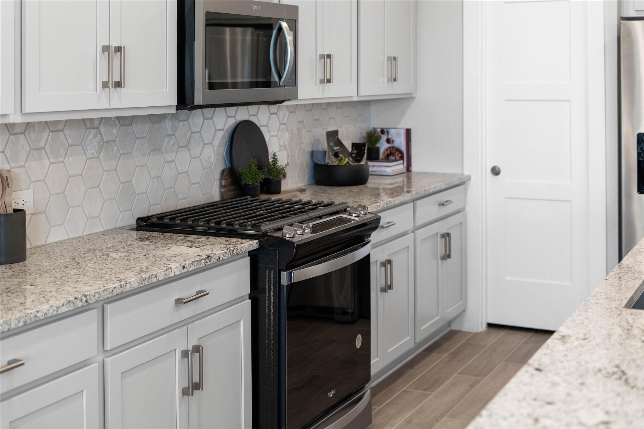 Showcased here is a Whirlpool gas range, paired with a steam microwave equipped with sensor cookingall framed by an elegant tile backsplash.