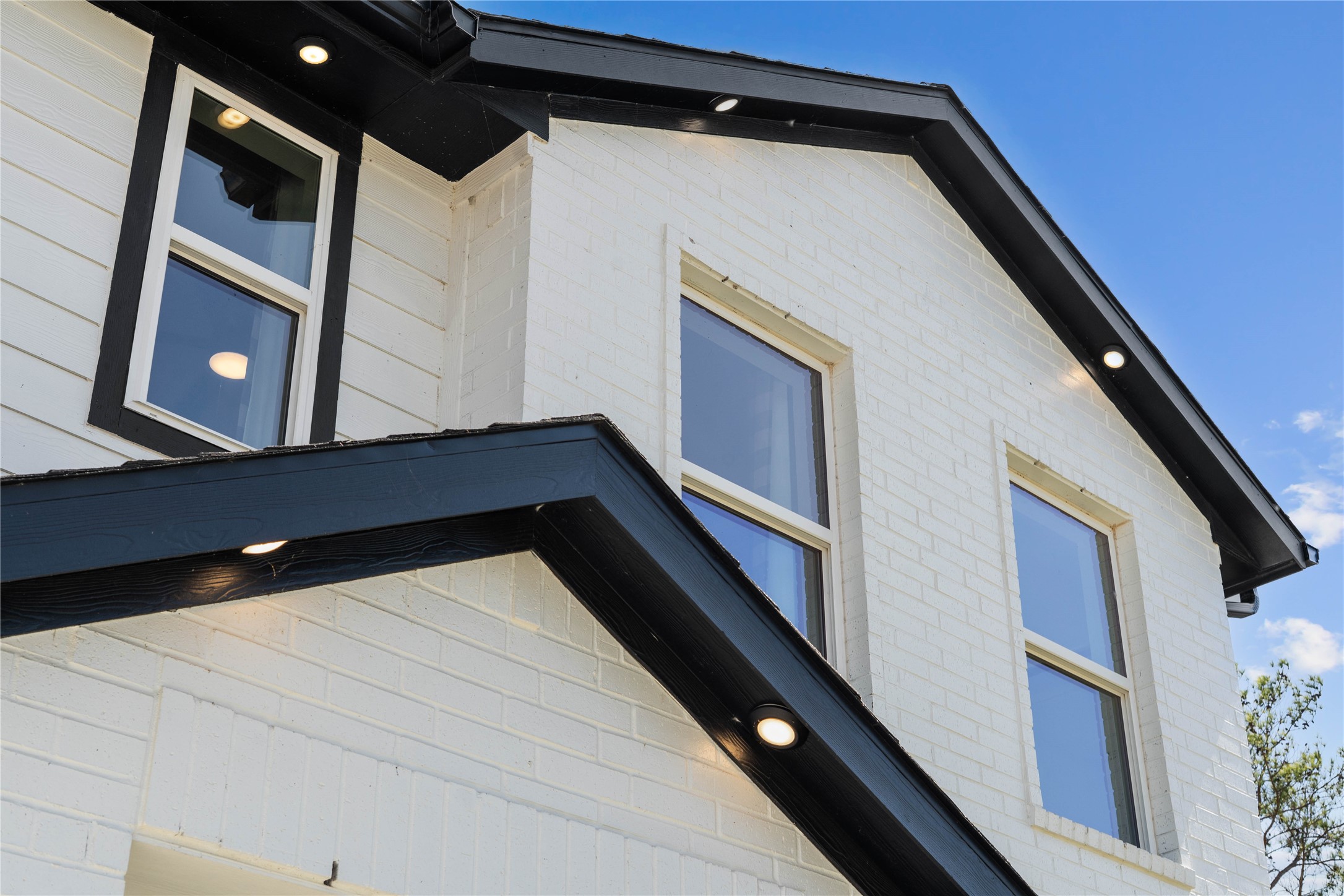 Make a bold statement with this stunning modern elevation, showcasing a high-contrast palette of crisp white siding and bold black architectural accents. The sophisticated roofline is defined by integrated recessed soffit lighting, providing an elegant nighttime glow and exceptional curb appeal.