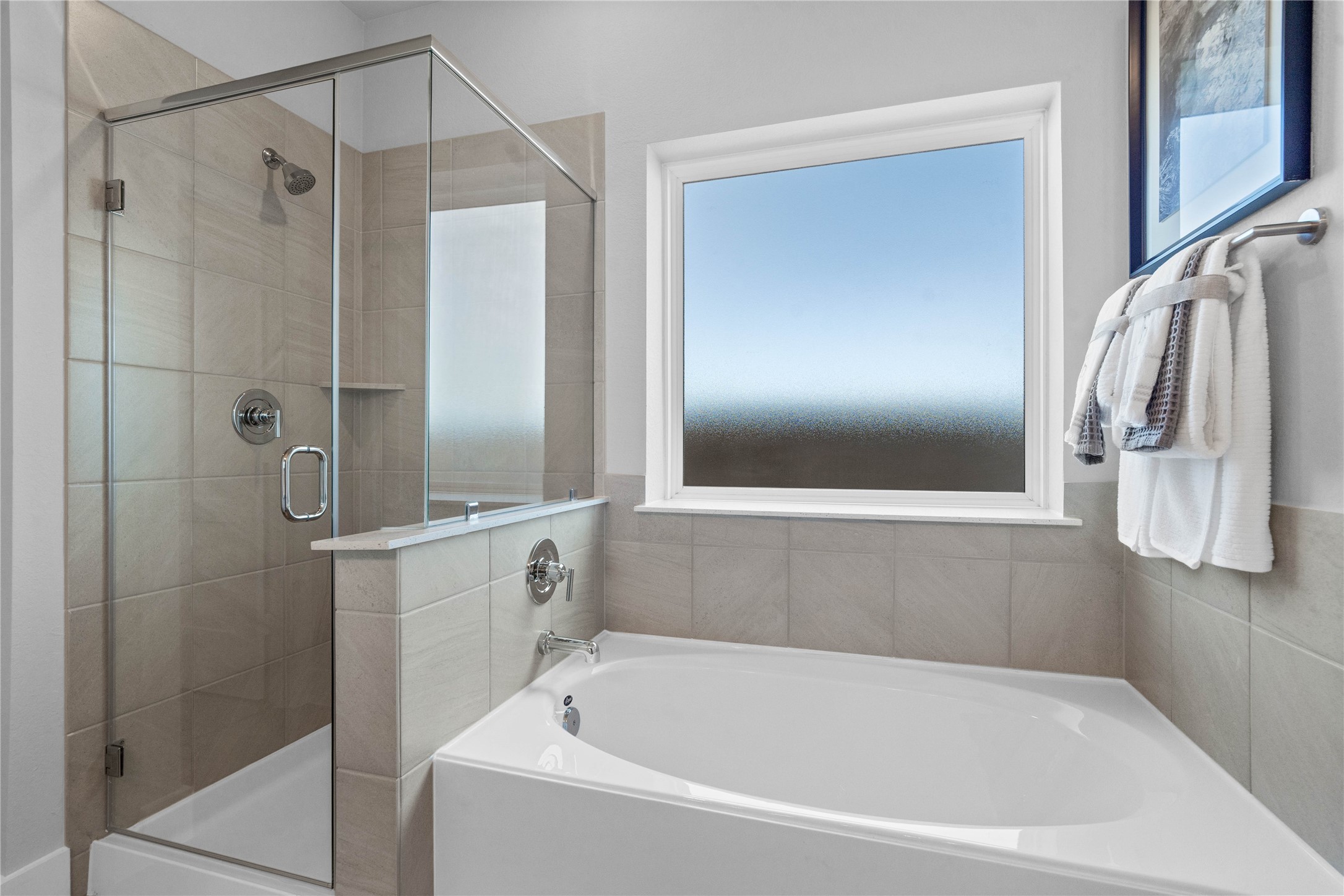 Additional view of the primary bathroom showcases the soaking tub and walk-in shower with obscure window allowing in natural lighting.