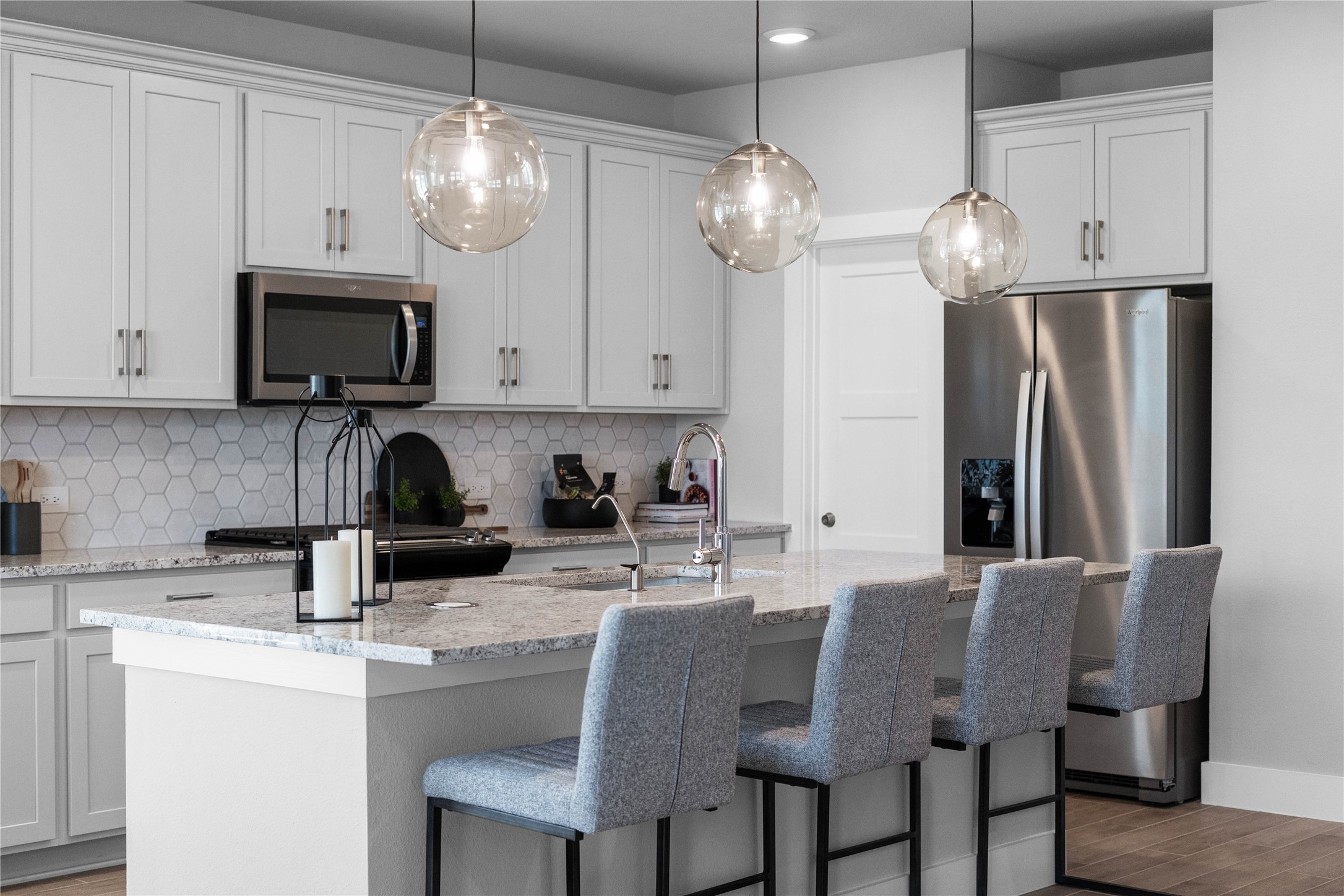 The extended granite kitchen island creates a convenient breakfast bar, providing a casual and inviting space where stools can be added for quick meals or long conversations.