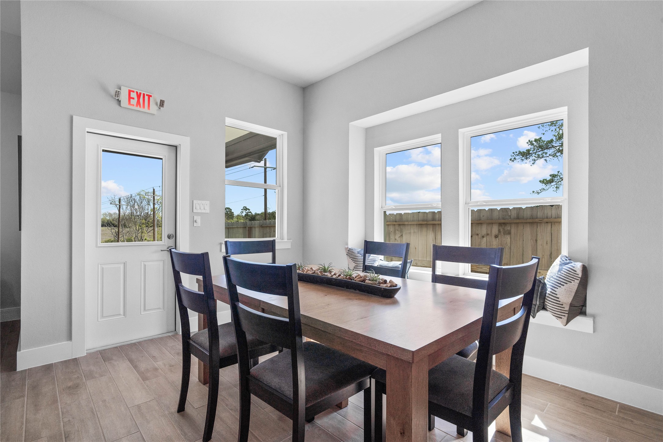 Enjoy meals in this sun-drenched space, featuring durable tile flooring, abundant natural light from the large windows, window seat, recessed lighting, and an access door to the back covered patio.