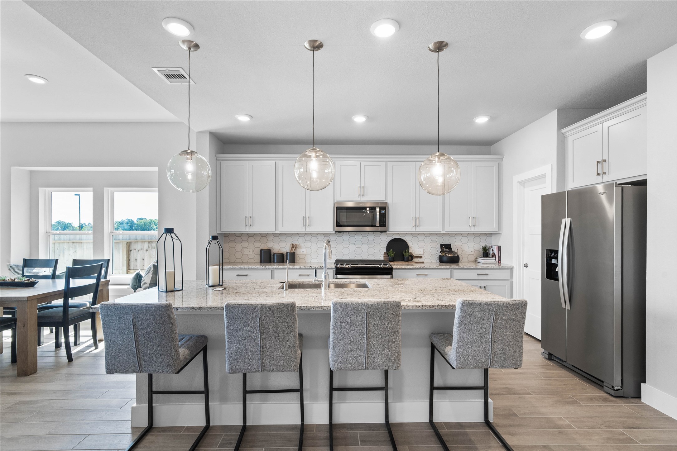 This modern kitchen island features a polished granite countertop with an undermount stainless steel sink, complemented by a Moen Sleek chrome faucet with DuPure water filtration system.