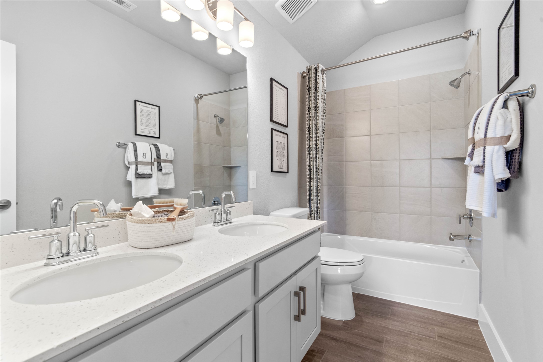 A streamlined secondary bathroom providing a functional tub/shower combination, double sinks, and modern fixtures, seamlessly blending practicality and style.