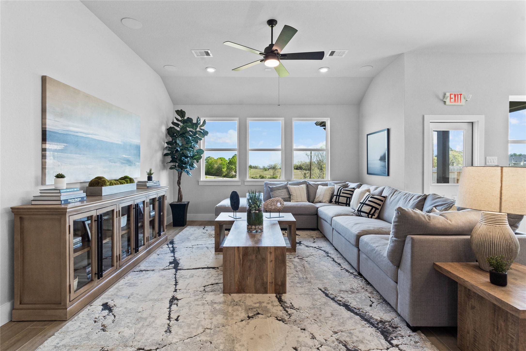 This sun-drenched sanctuary where soaring sloped ceilings and wood-look tile flooring meet. This seamless open-concept space is perfectly illuminated by recessed lighting and a wall of windows, while a ceiling fan keeps the room comfortable year-round.