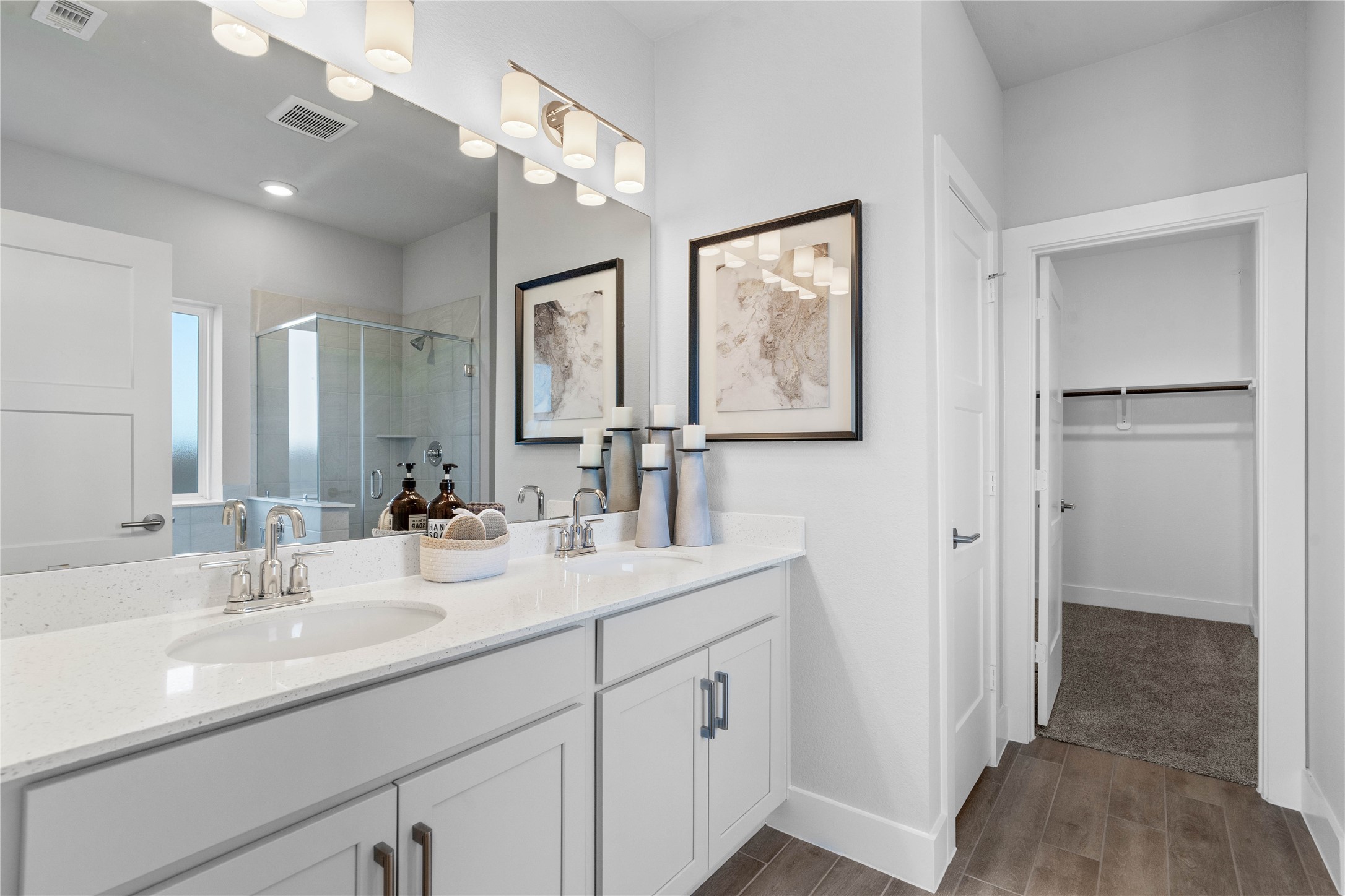 A bright and functional primary bath offering dual sinks for busy mornings, a large mirror, soaking tub, and a modern glass-enclosed shower, creating a serene and efficient space.