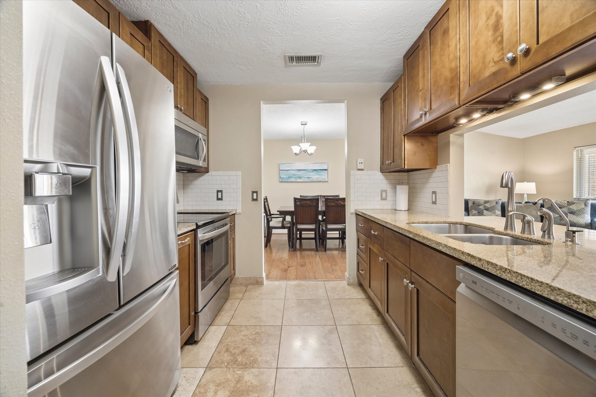 Updated galley kitchen with granite countertops, rich wood cabinetry, stainless steel appliances, and excellent storage, with an open sightline toward the adjoining living and dining areas. Updated galley kitchen with granite countertops, rich wood cabinetry, stainless steel appliances, and excellent storage, with an open sightline toward the adjoining living and dining areas.