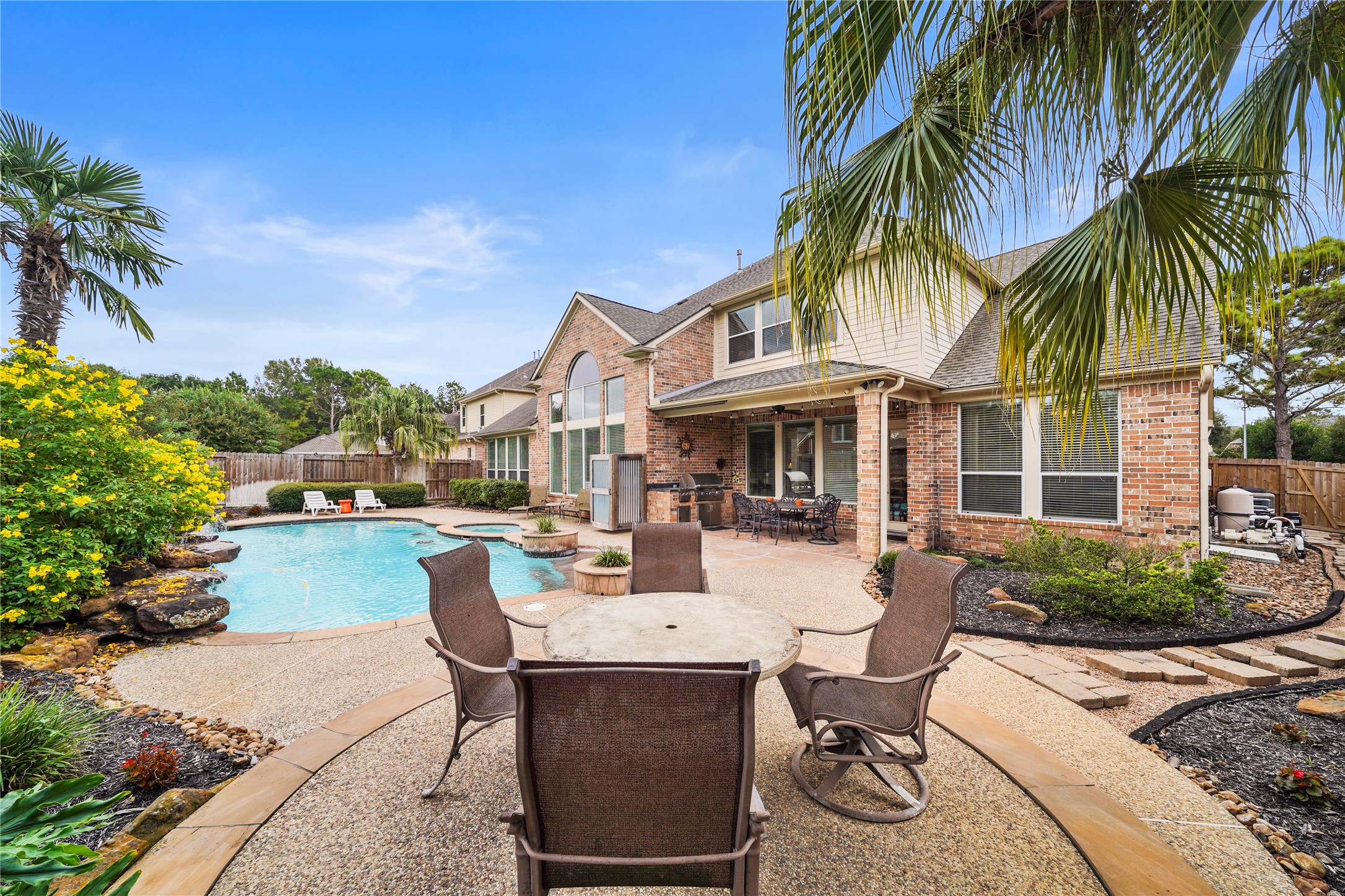 Framed by tropical landscaping and generous patio space, the pool and spa create a private backyard escape for sunny Texas days.
