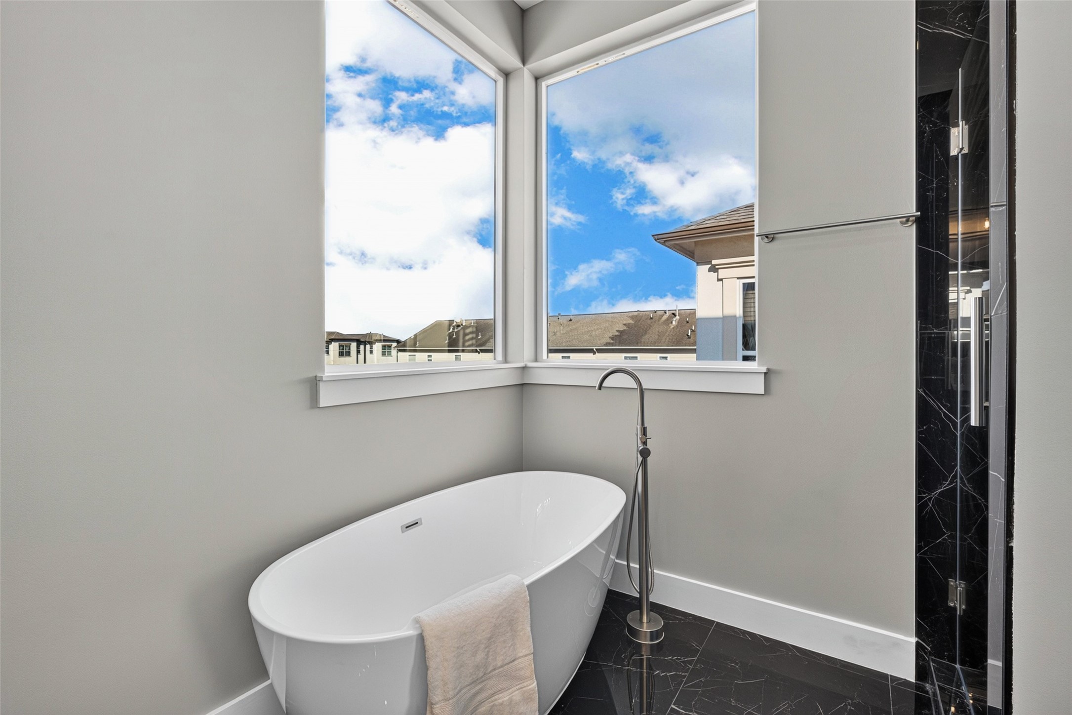 Spa-like primary bath retreat with a standalone soaking tub surrounded by large corner windows that fill the space with natural light.