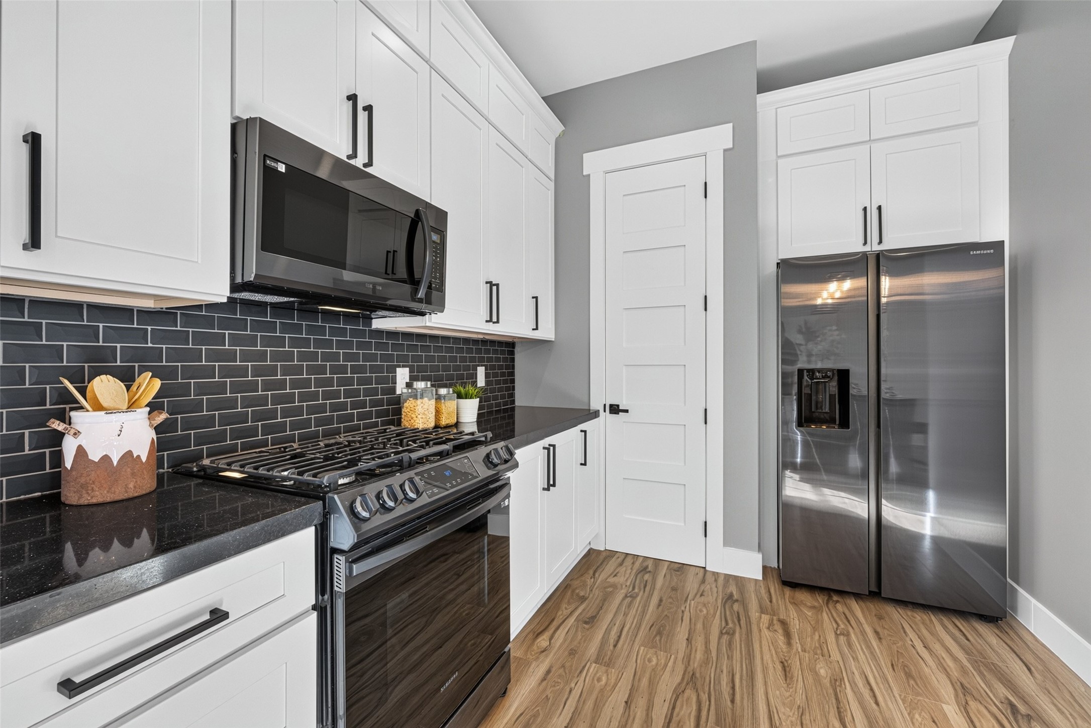 Equipped with high-end stainless steel appliances, including a French door refrigerator, gas range, built-in microwave, and dishwasher.