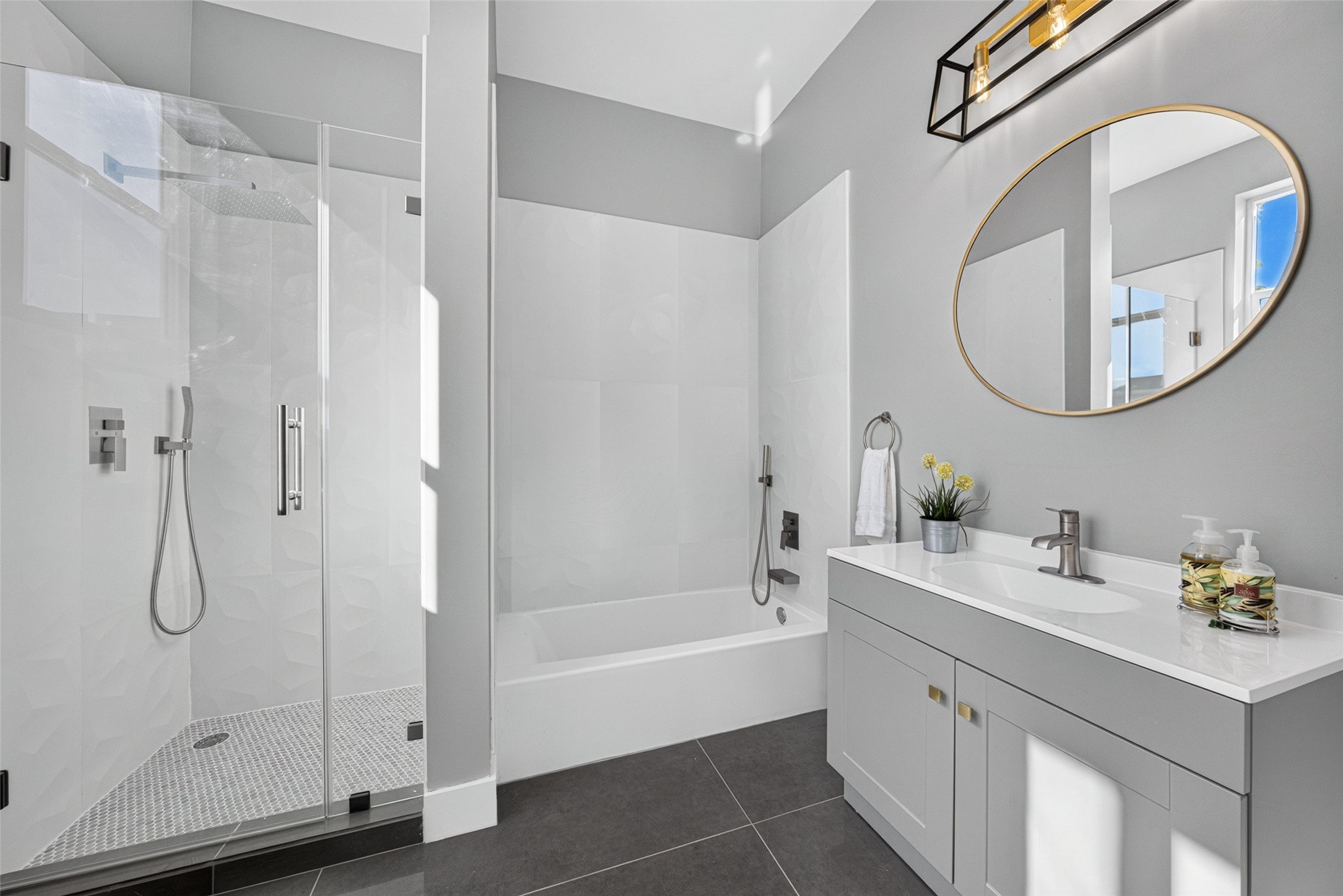 Modern first-floor bathroom featuring a sleek round mirror, clean white subway tile, and a stylish glass-enclosed shower.