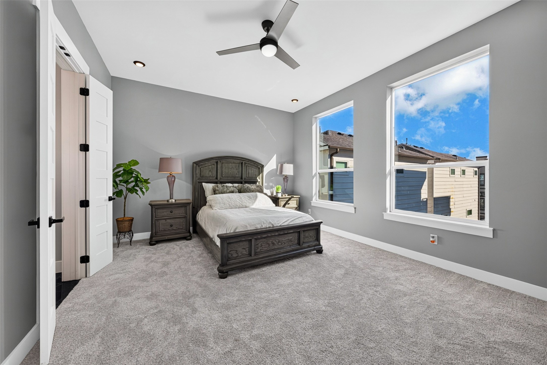 This luxurious primary bedroom serves as a peaceful, sunlit retreat within the home.