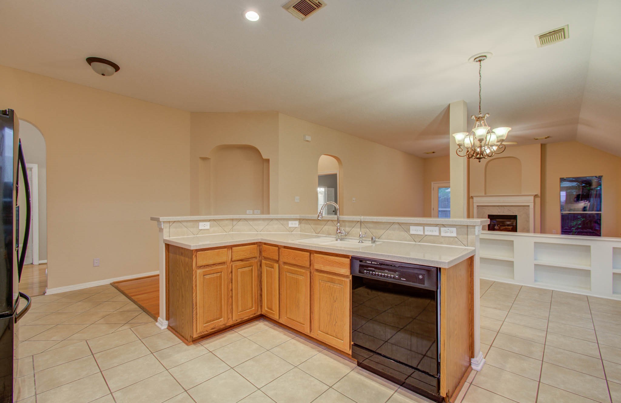 Spacious open-concept kitchen with a central island, ample counter space, and a view of the cozy living area featuring a fireplace and built-in shelving.