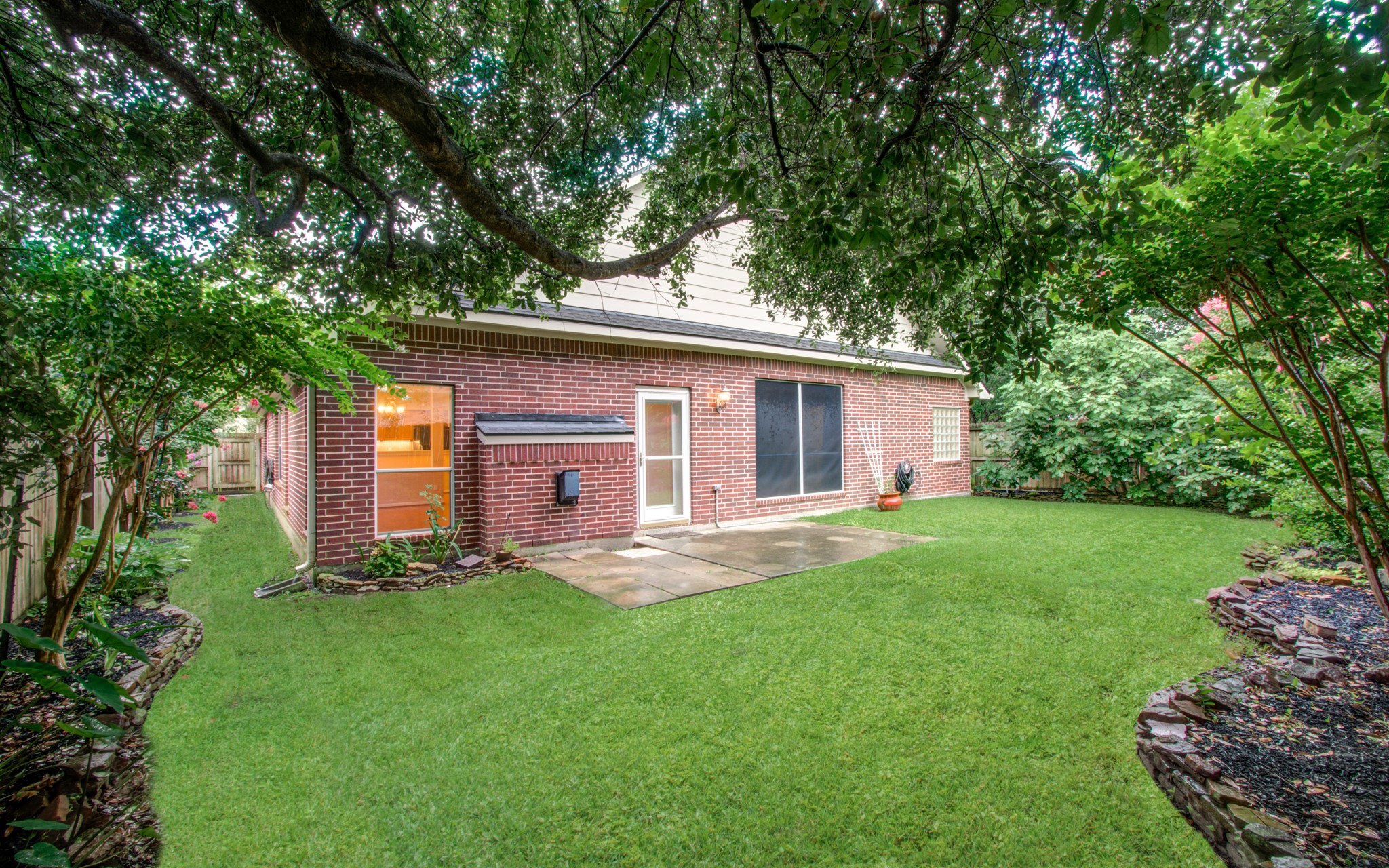 Charming backyard with lush greenery and a spacious patio, perfect for outdoor entertaining.