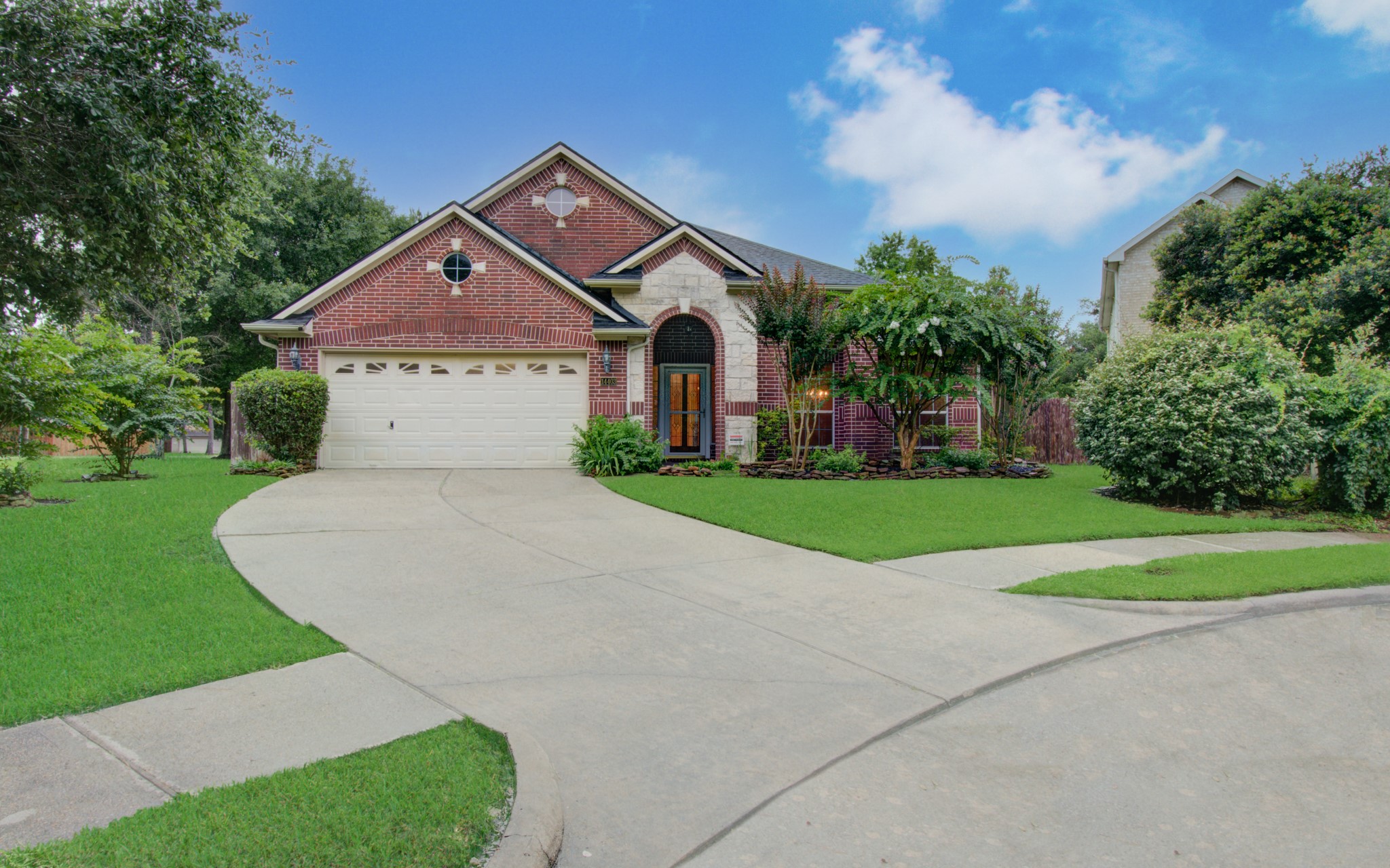 Charming brick home with a welcoming arched entryway, beautifully landscaped front yard, and a spacious two-car garage, nestled in a serene neighborhood.
