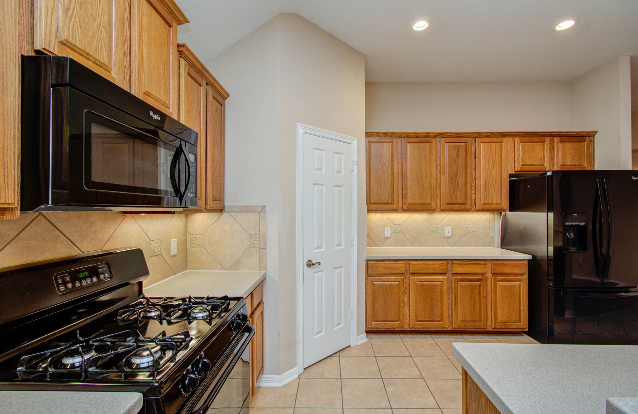 Spacious kitchen with warm wood cabinetry, sleek black appliances, and ample counter space for cooking and entertaining.