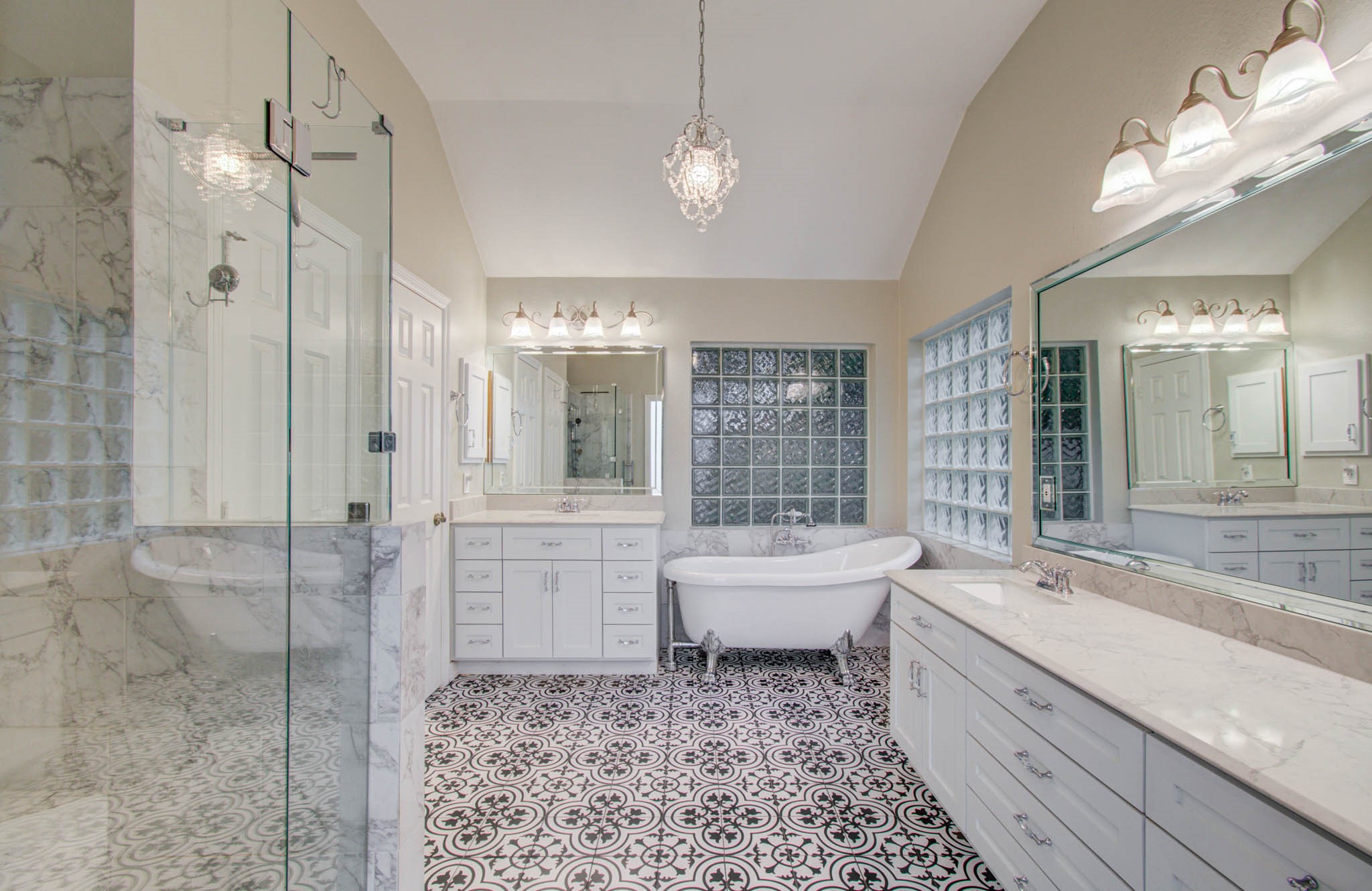 Elegant bathroom featuring a luxurious clawfoot tub, spacious glass-enclosed shower, and stylish patterned tile flooring, all complemented by chic lighting and ample counter space.